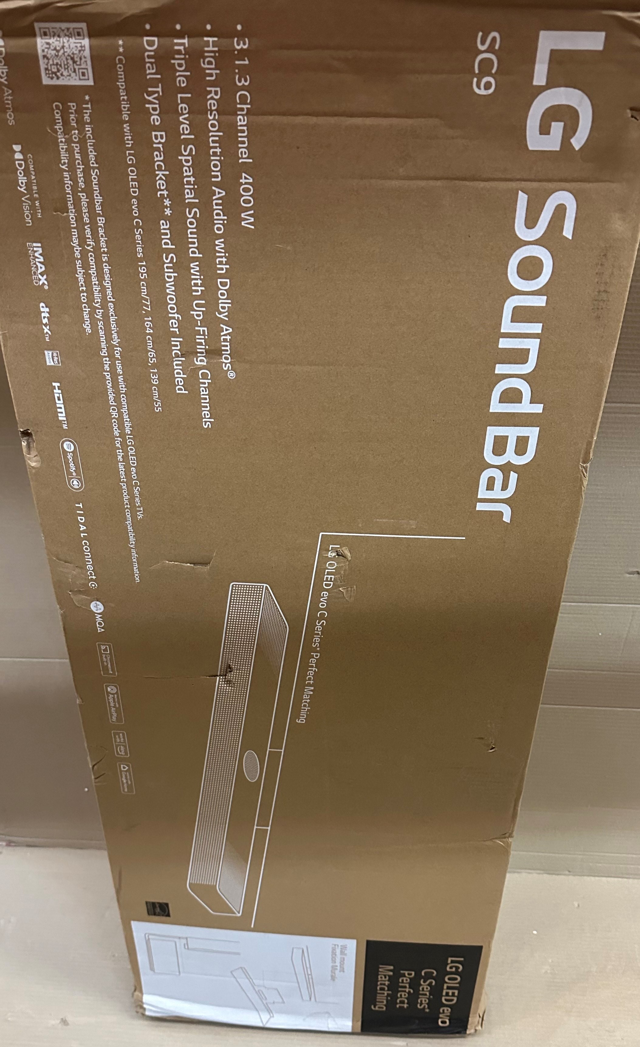 Kartonowe pudełko soundbaru LG SC9 ze szczegółami produktu i logo Dolby Atmos.
