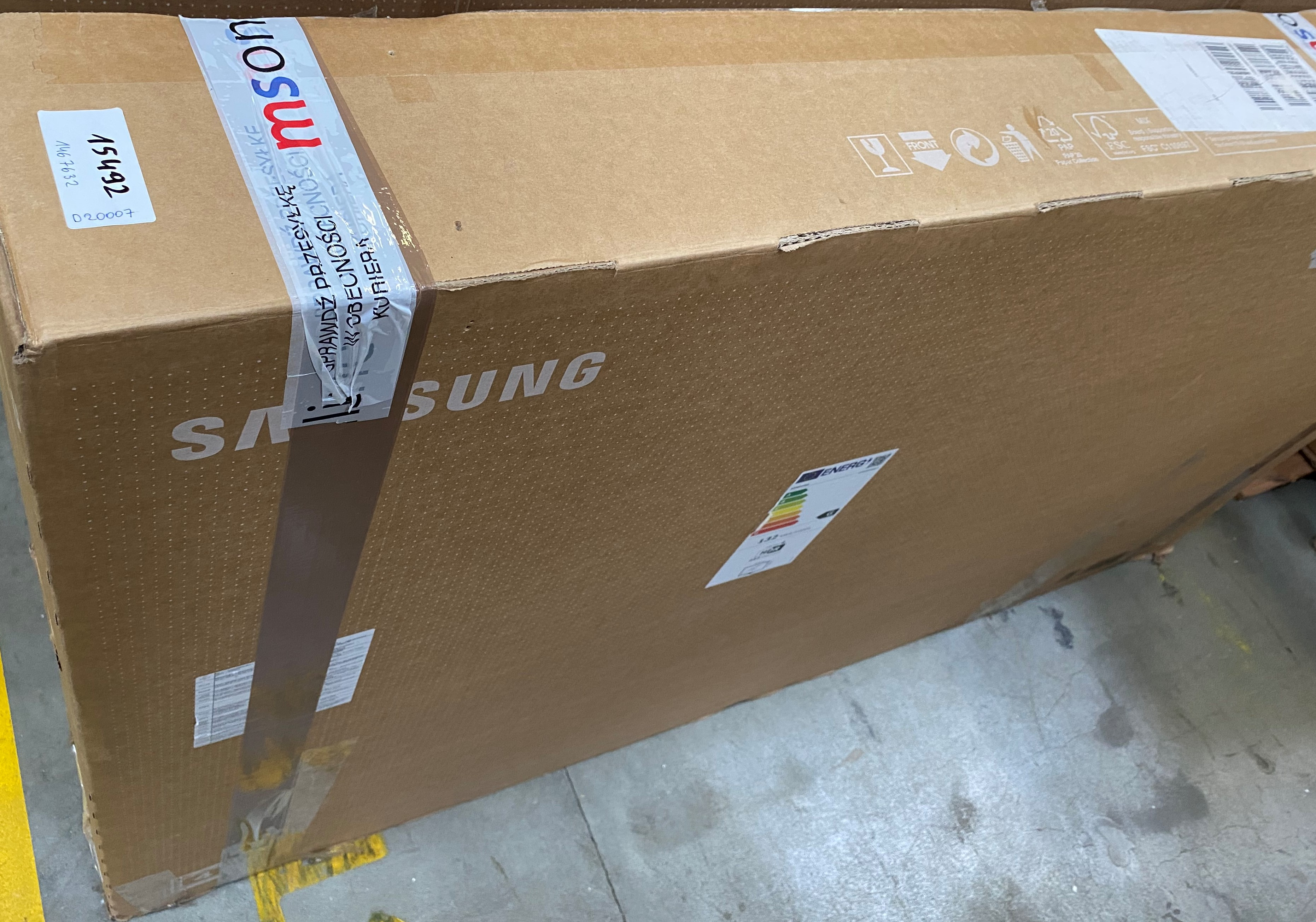 Duże kartonowe pudełko, zaklejone taśmą, z logo i etykietami.