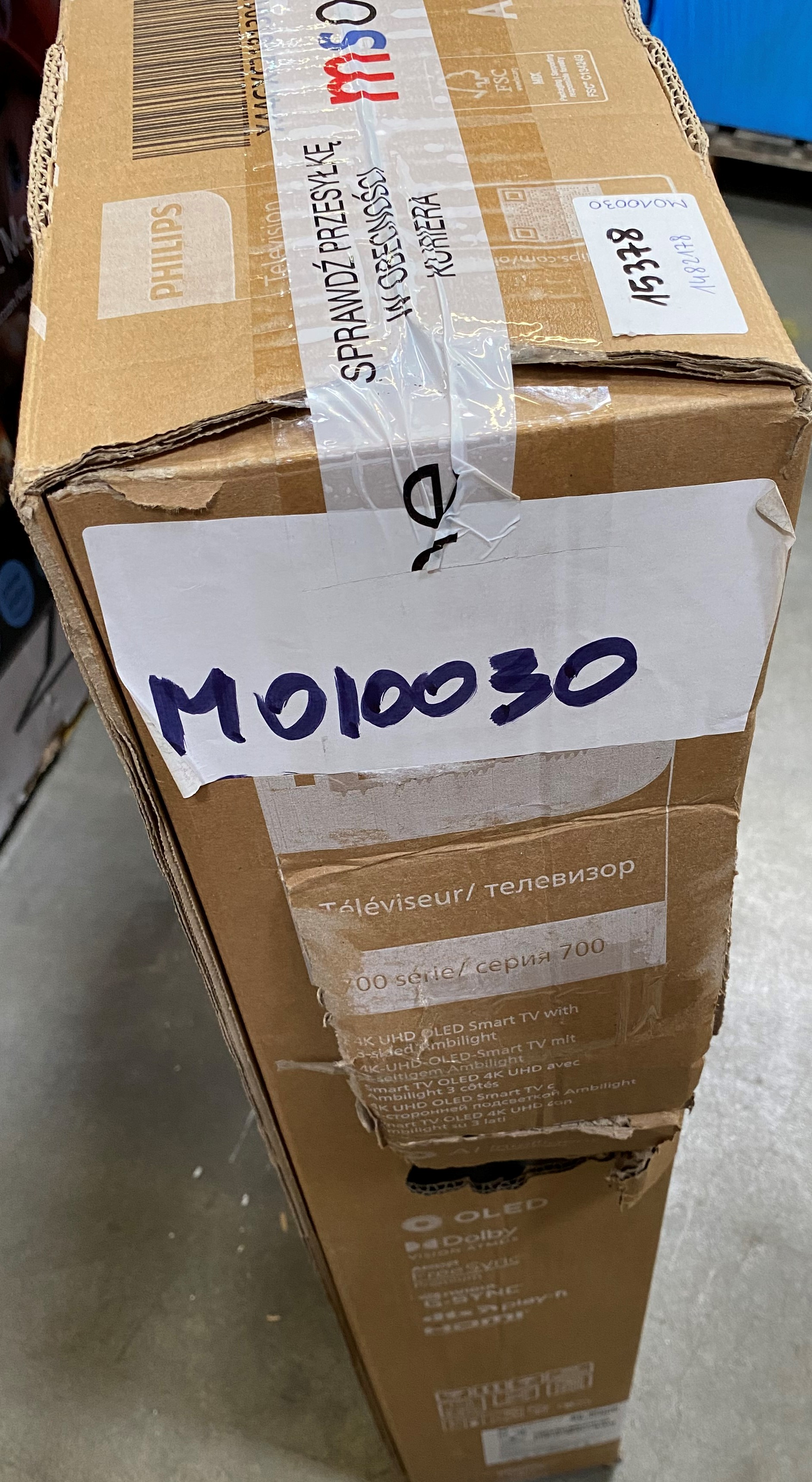 Kartonowe pudełko z etykietami i taśmą jest zaklejone. Tekst: M010030, Philips.