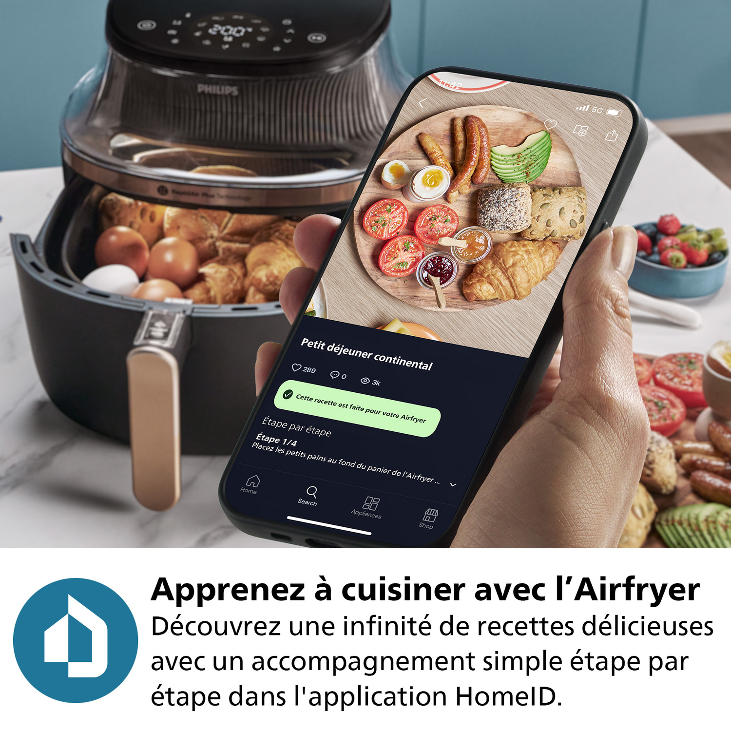 Une personne tient un téléphone affichant une recette de petit-déjeuner continental à côté d'une friteuse à air.