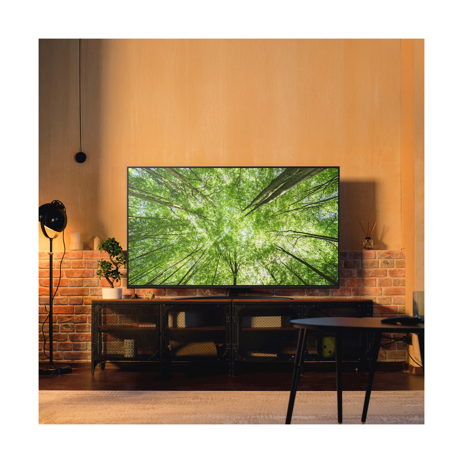Soggiorno con TV su mobile, muro di mattoni e una lampada.