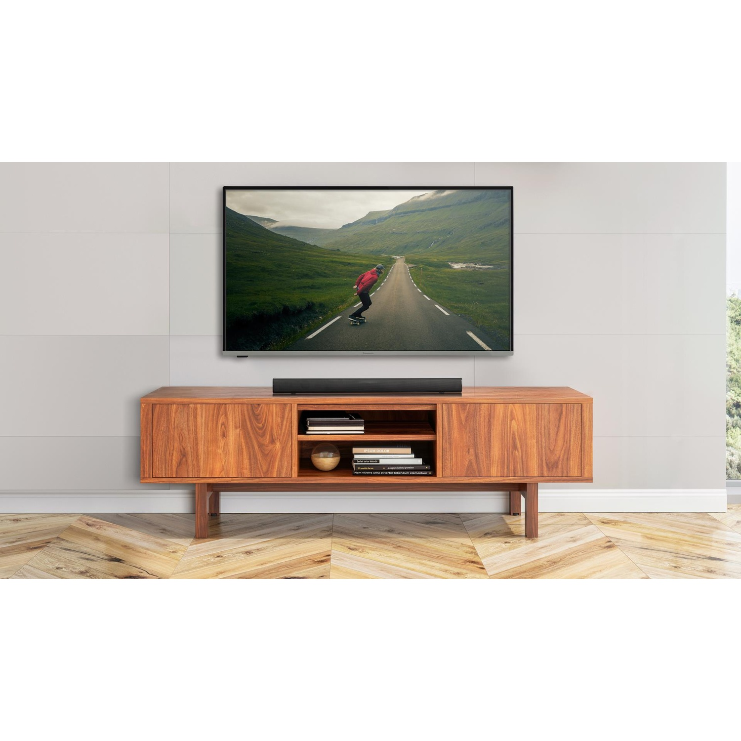 TV e soundbar su un mobile in legno. La TV mostra una persona che fa skateboard su una strada.