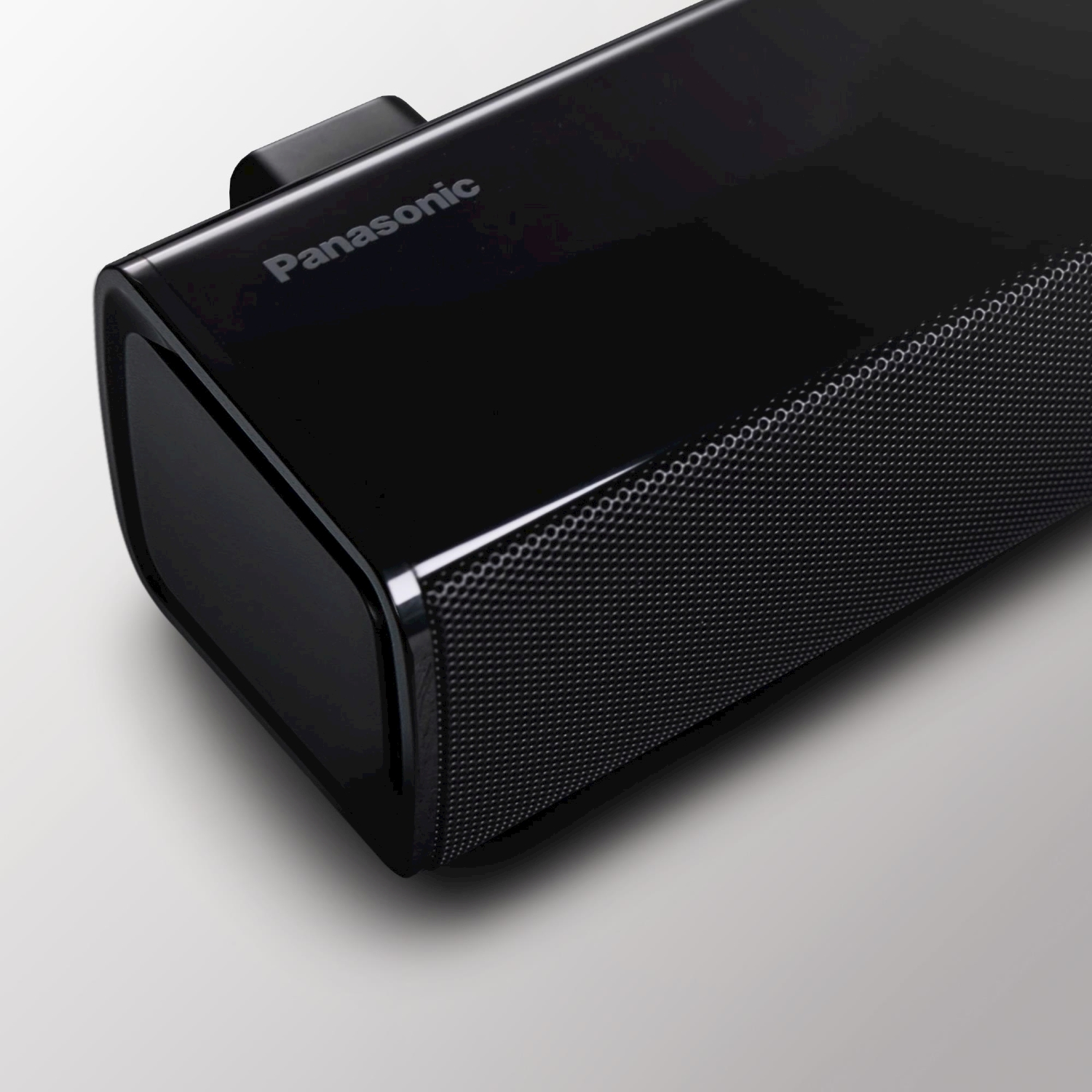 Una soundbar nera con una parte anteriore in rete su sfondo bianco.