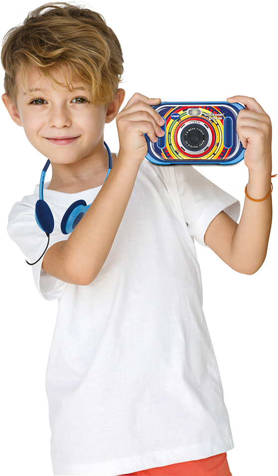 Ein Junge hält eine bunte Spielzeugkamera und lächelt, trägt Kopfhörer. Weißer Hintergrund.
