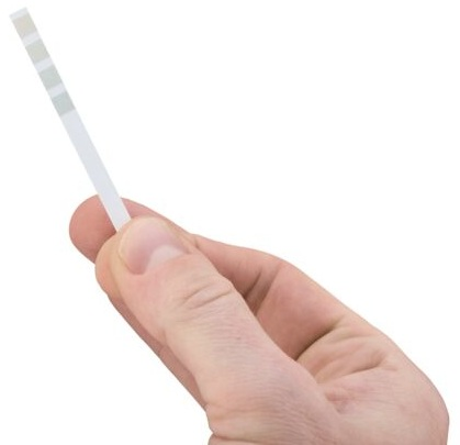 Ręka trzymająca pasek testowy. Pasek testowy ma na sobie zielone i szare linie.