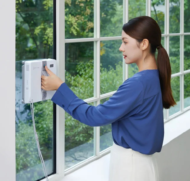 Kobieta czyszcząca okno za pomocą robota do mycia okien.