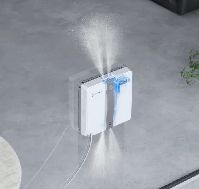 Myjka do okien rozpyla wodę na oknie.