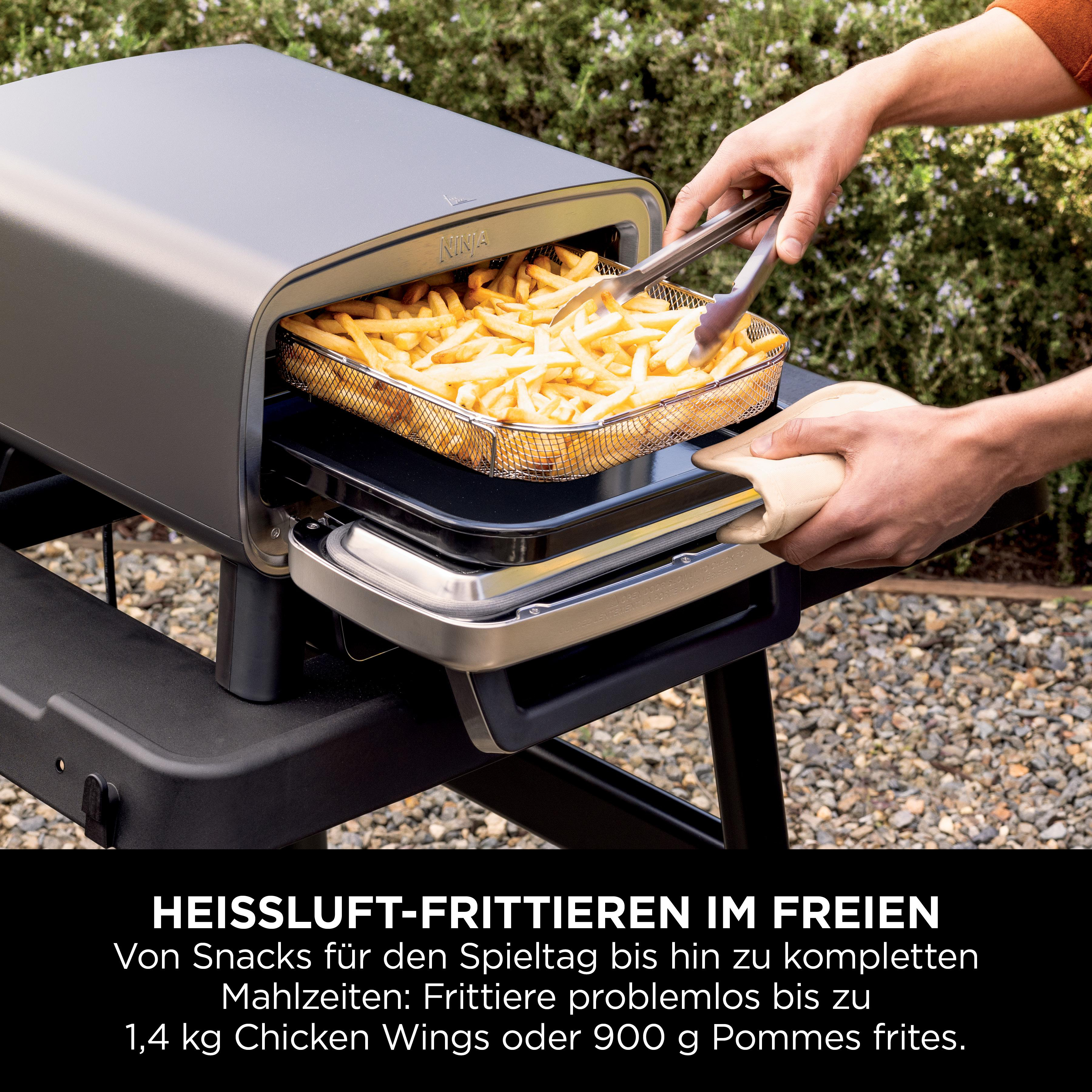 Person nimmt Pommes mit Zange aus der Fritteuse, im Freien.