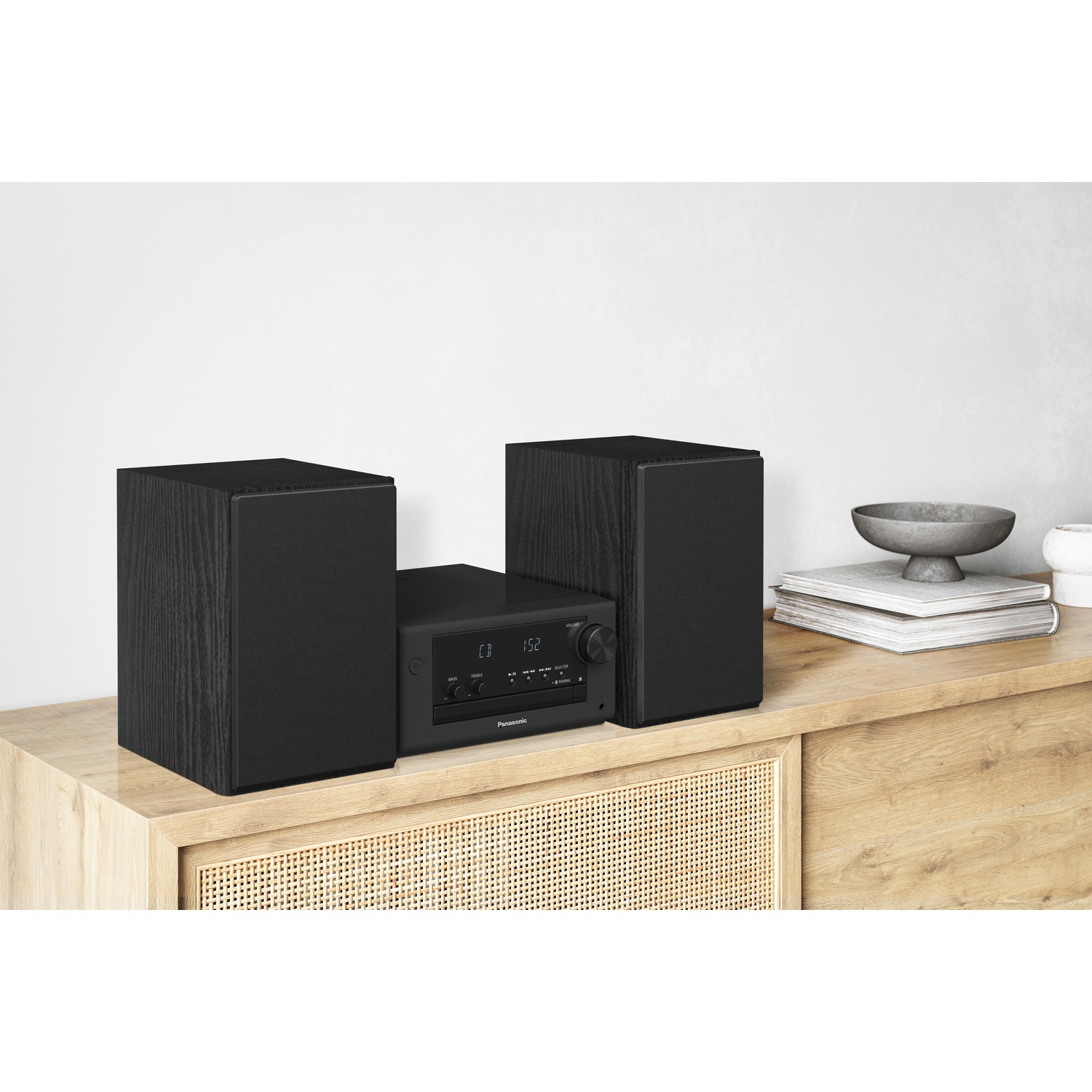 Stereo nero con altoparlanti su mobile in legno. Parete bianca sullo sfondo.