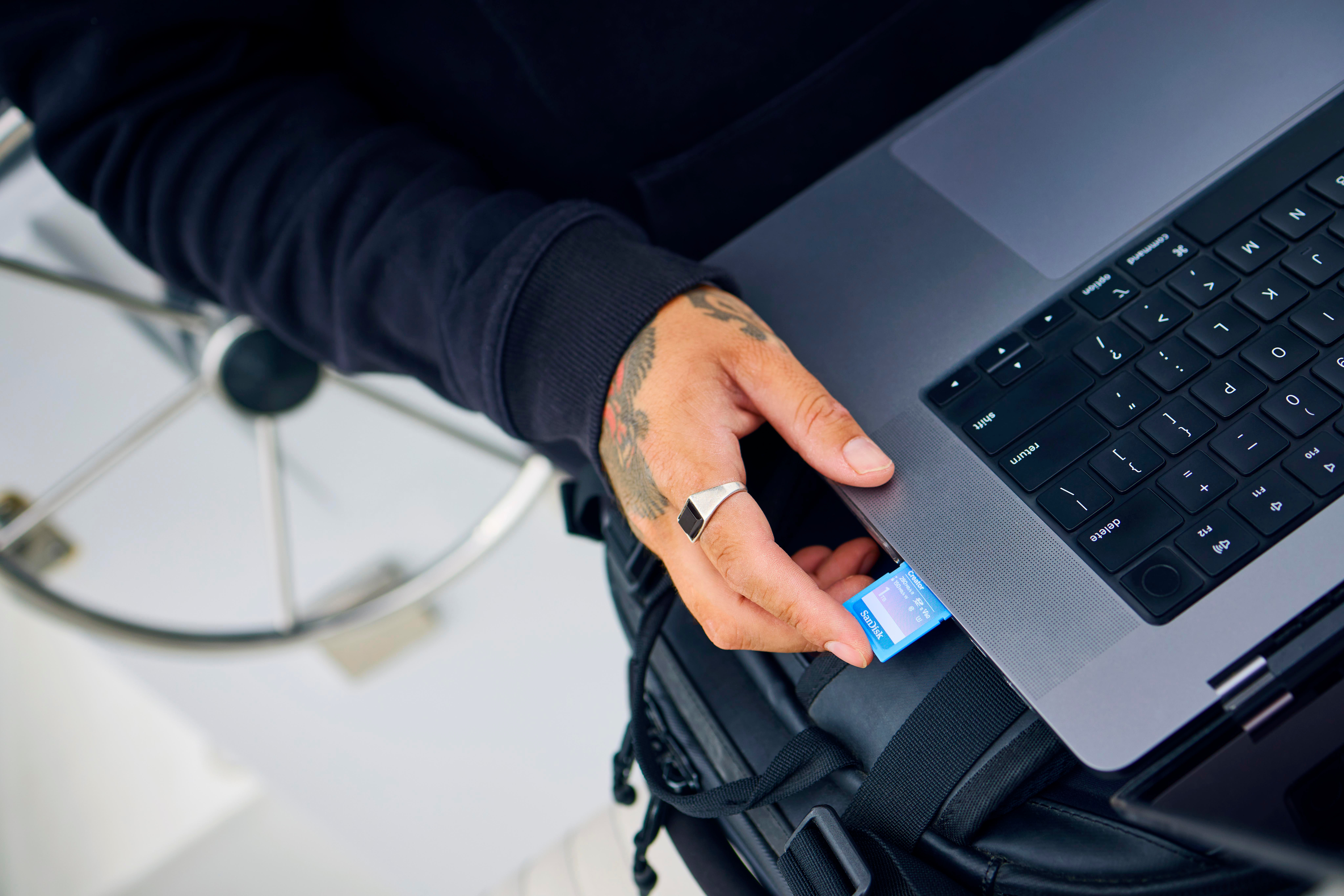 Eine Person steckt eine blaue SD-Karte in einen Laptop.