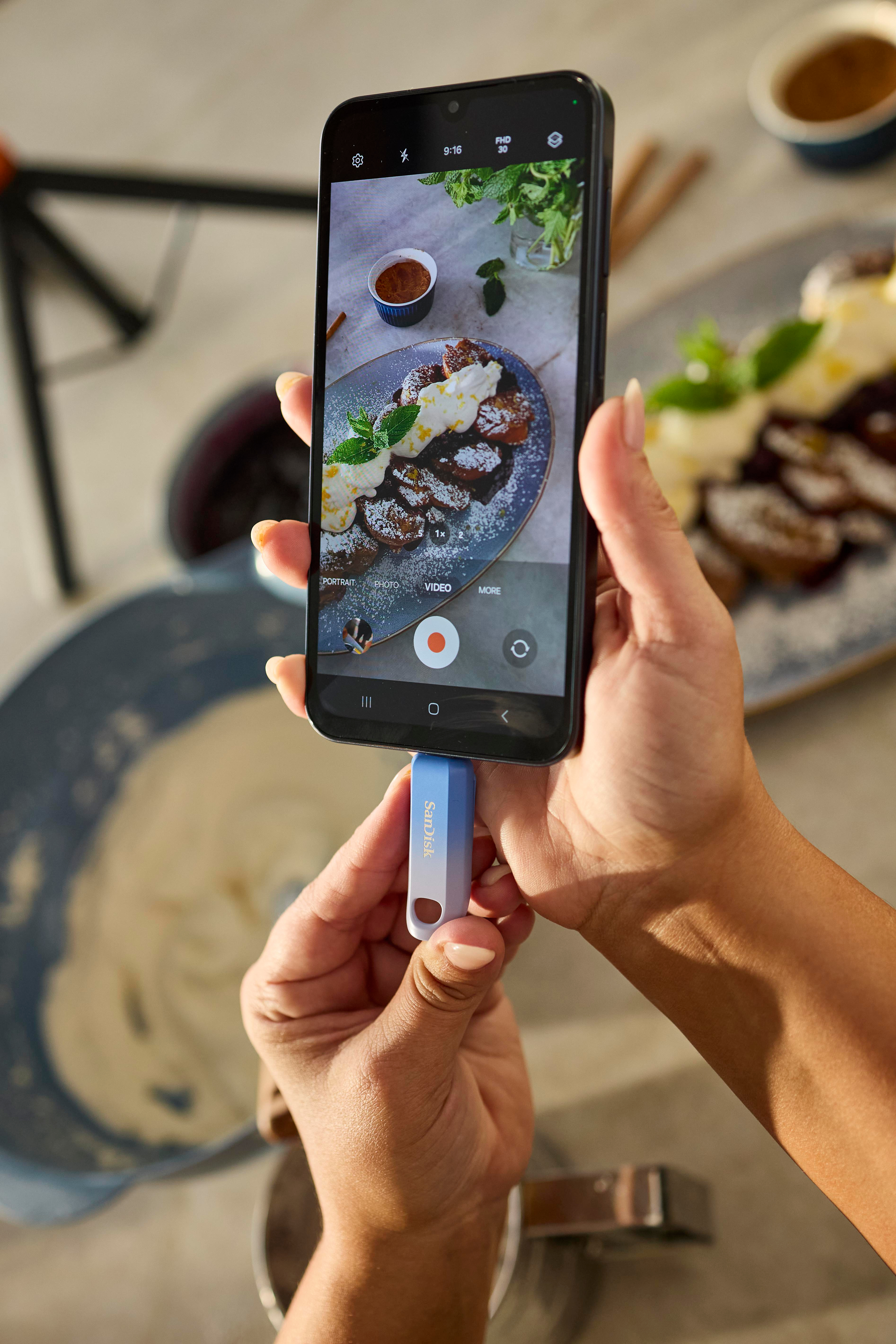 Person hält Telefon mit USB-Stick, Essen auf dem Bildschirm.