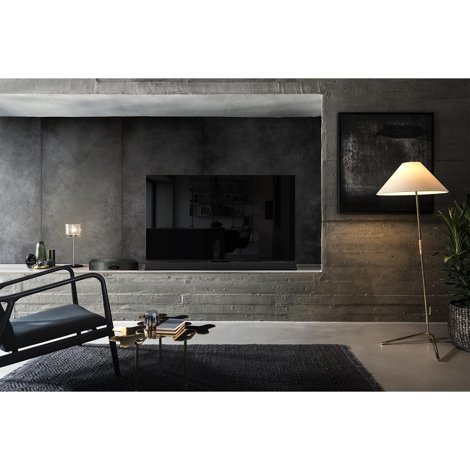 Soggiorno moderno con TV in una nicchia a muro, una sedia nera, una lampada da terra e un tappeto scuro.