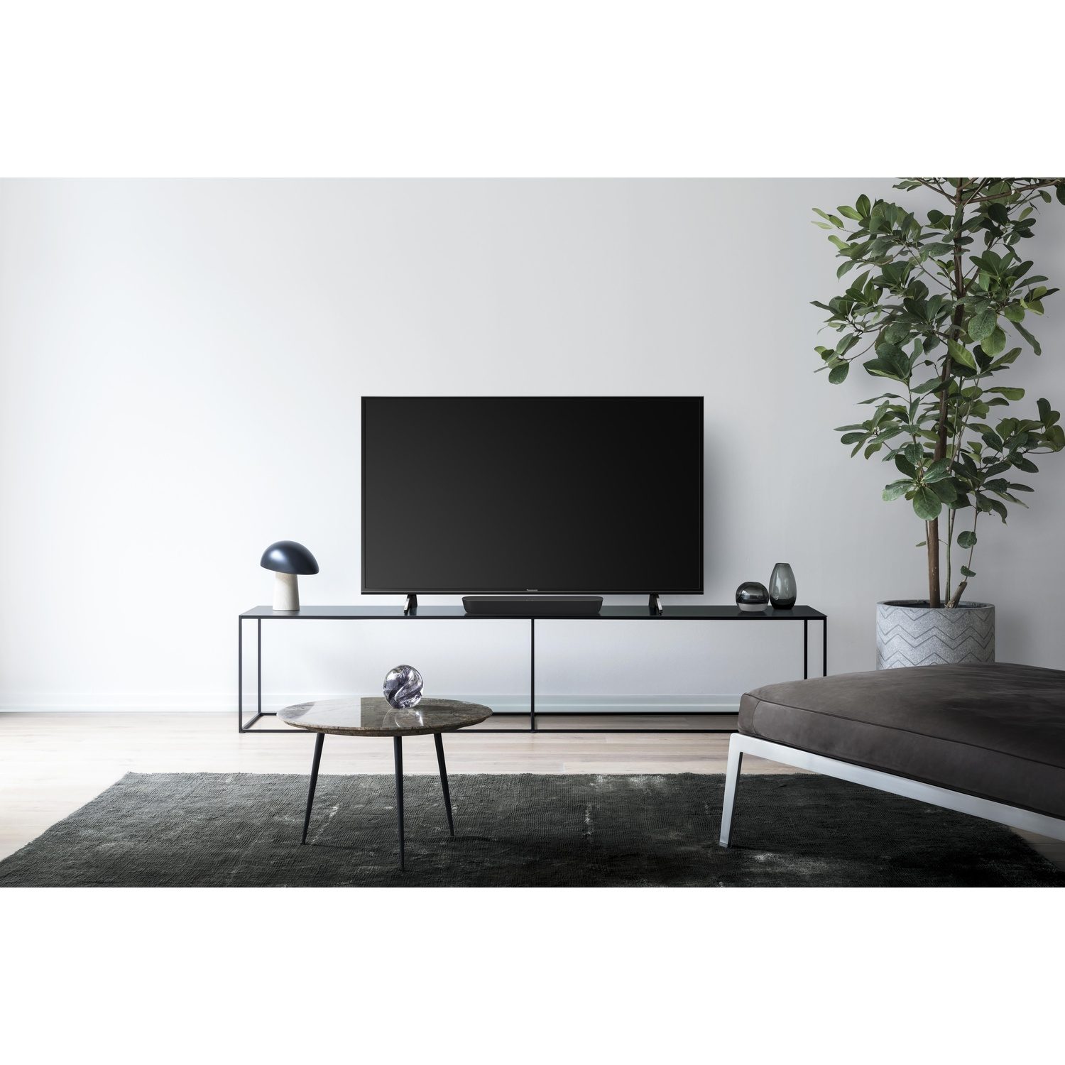 Soggiorno: TV su mobile bianco, arte, divano e pianta.