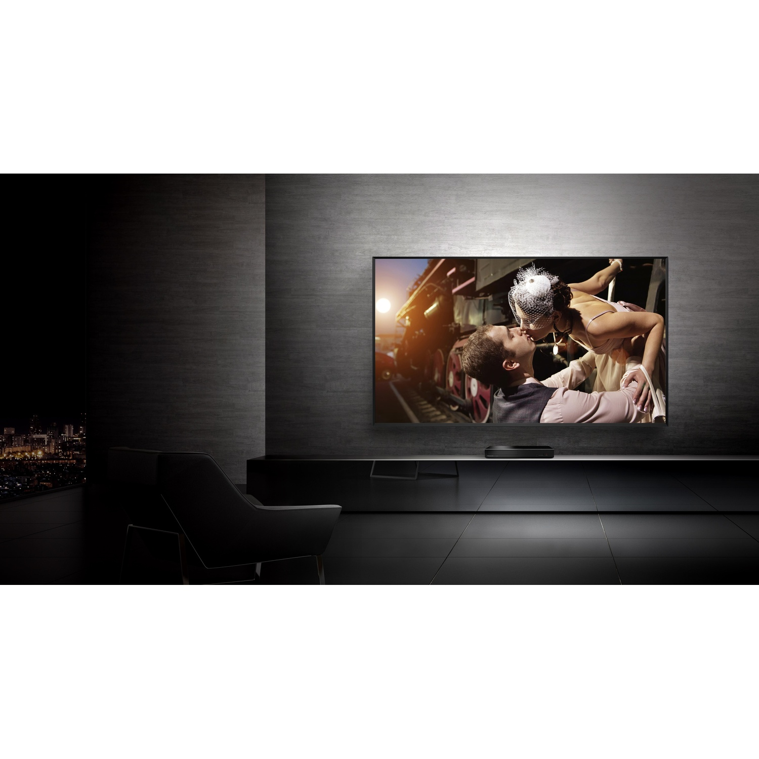 Una grande TV mostra una scena di matrimonio, stanza nera, mobili scuri, luci della città.