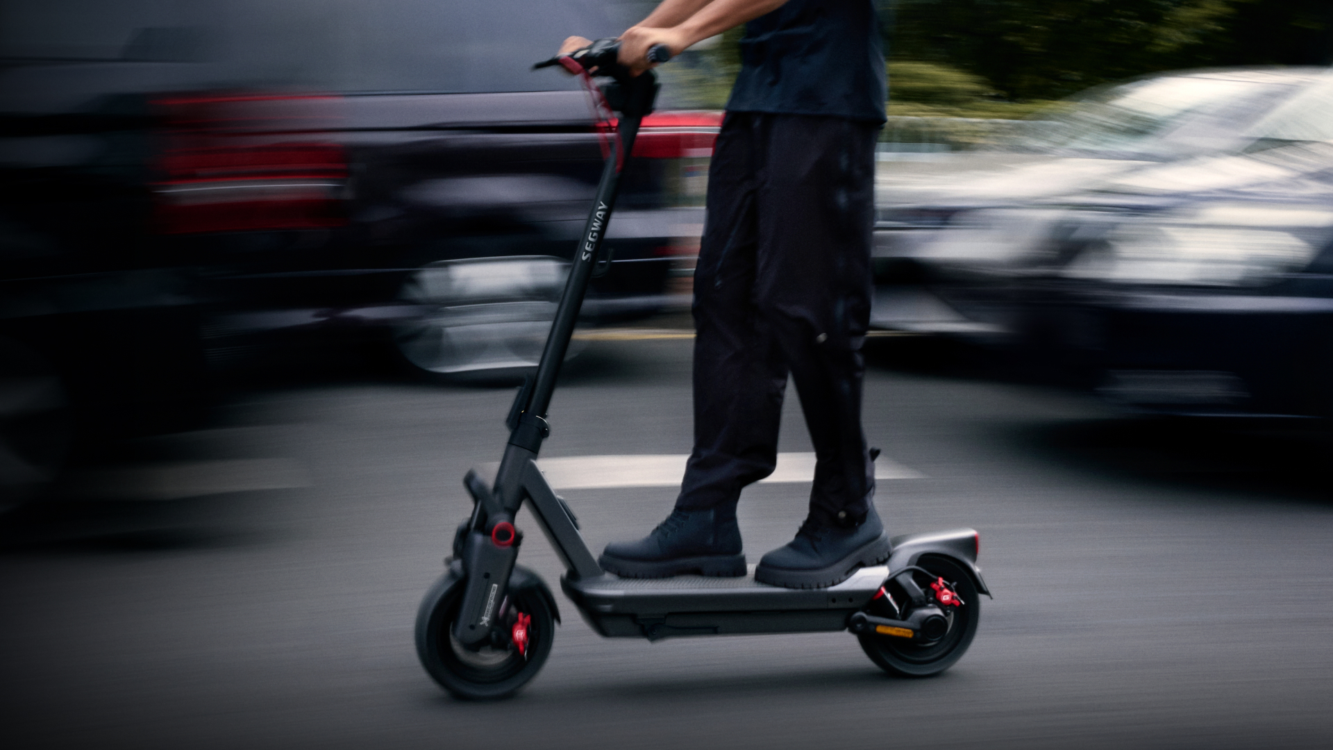 Person fährt einen schwarzen elektrischen Segway-Roller auf einer Straße. Der Roller ist in Bewegung.