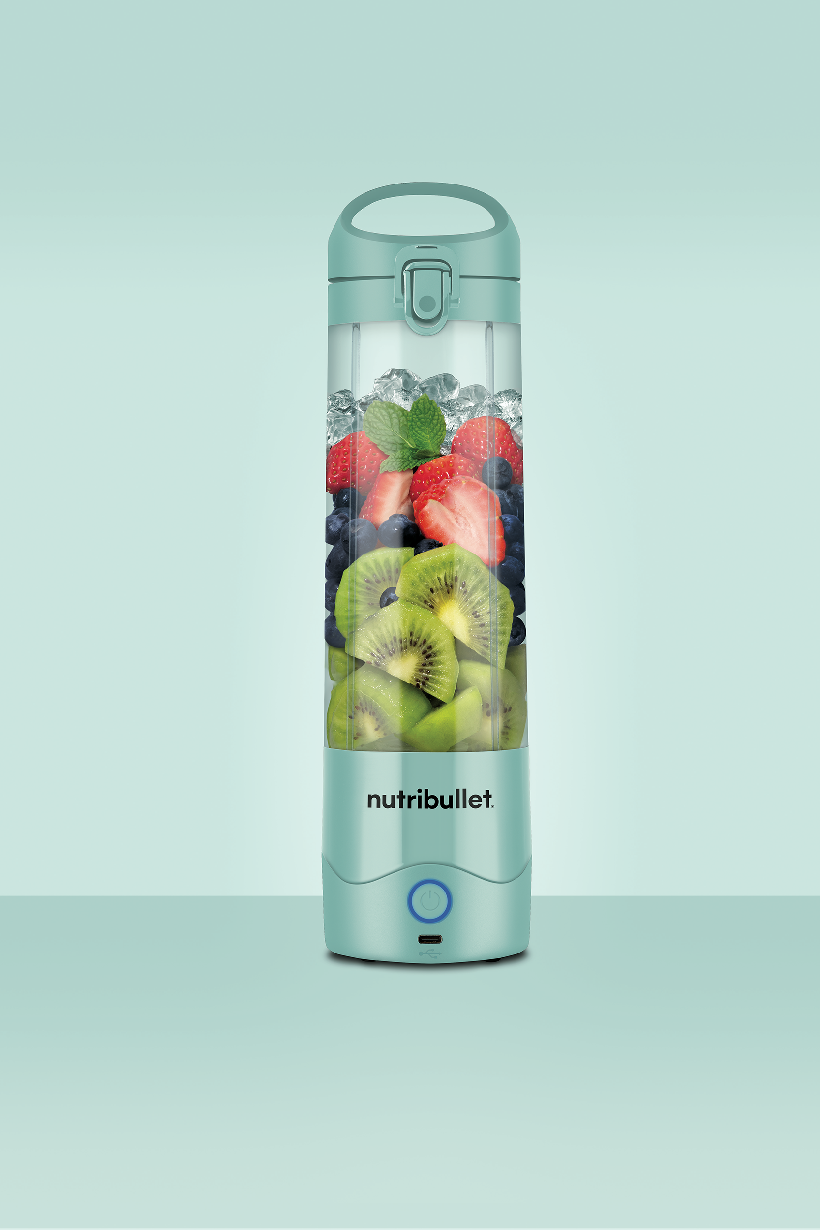 Nutribullet turmixgép gyümölcsökkel (kiwi, eper, áfonya) és jéggel. Mentazöld szín.