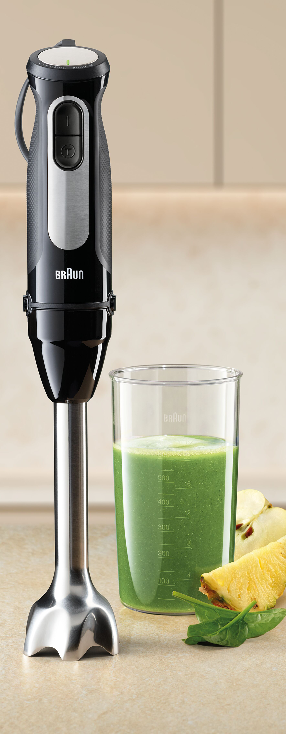 Fekete Braun botmixer zöld turmixszal, almával és ananász szeletekkel világos felületen.