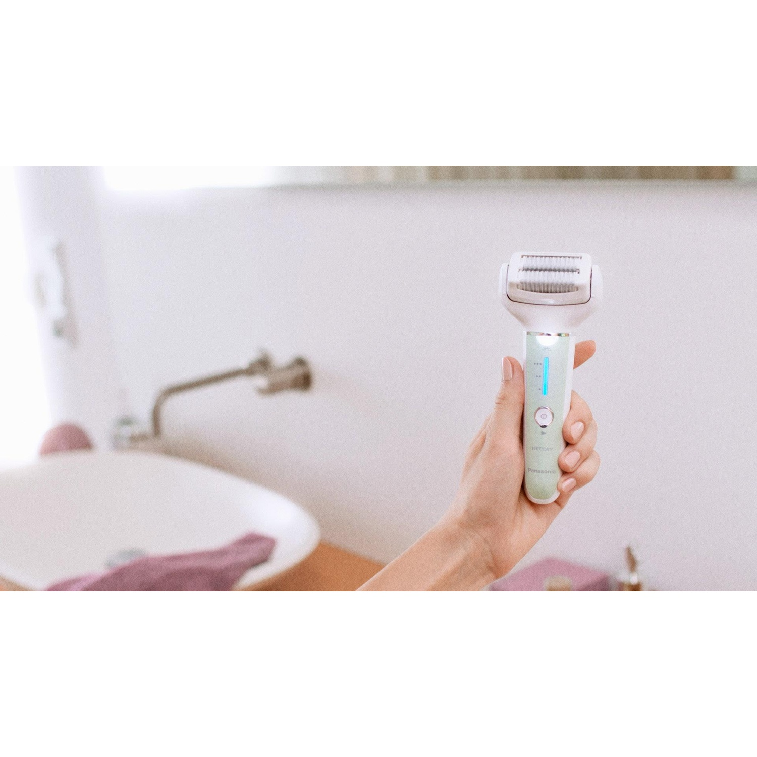La mano di una donna tiene un rasoio Panasonic umido/asciutto in un bagno.