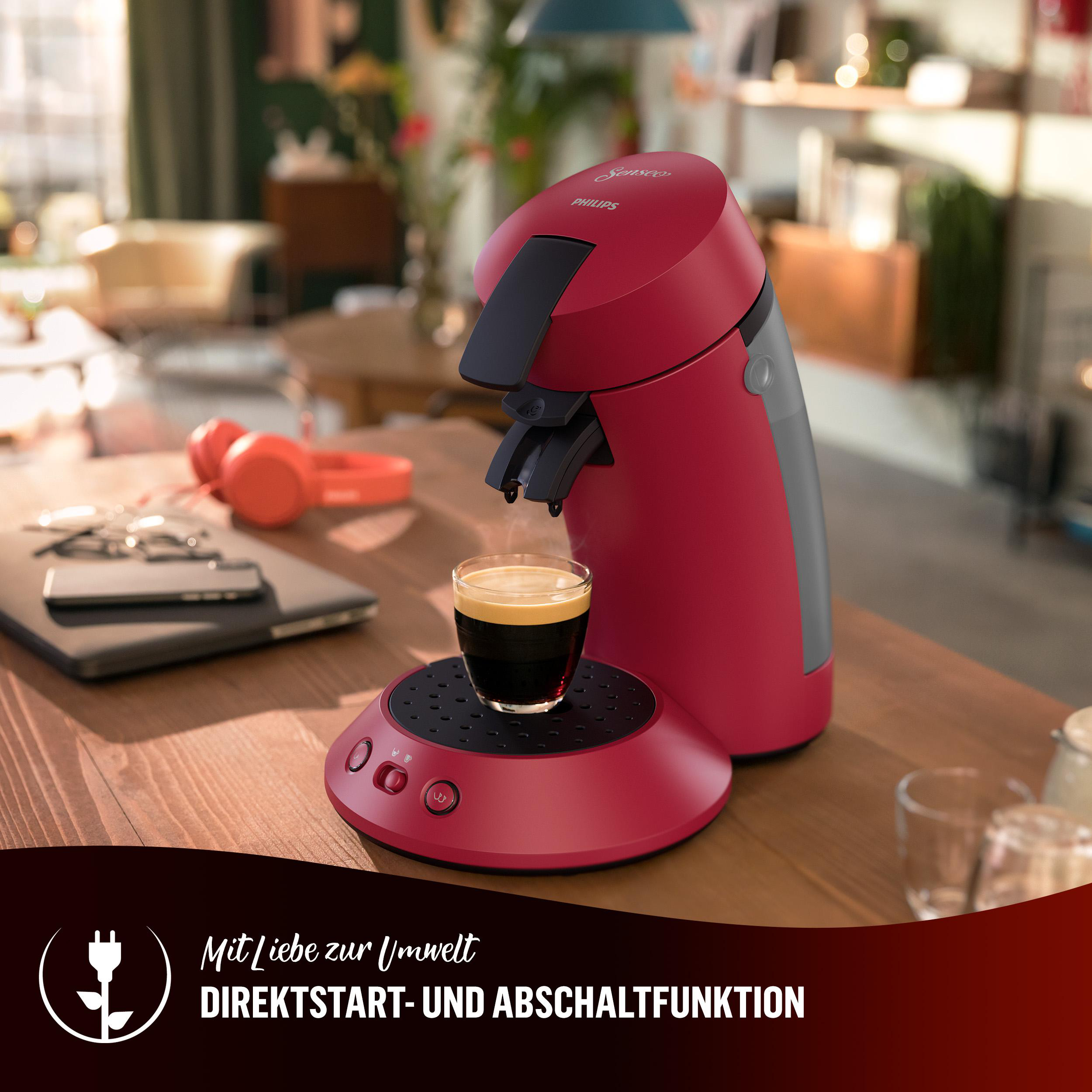 Rote Kaffeemaschine mit einem Glas Kaffee auf Holzoberfläche.