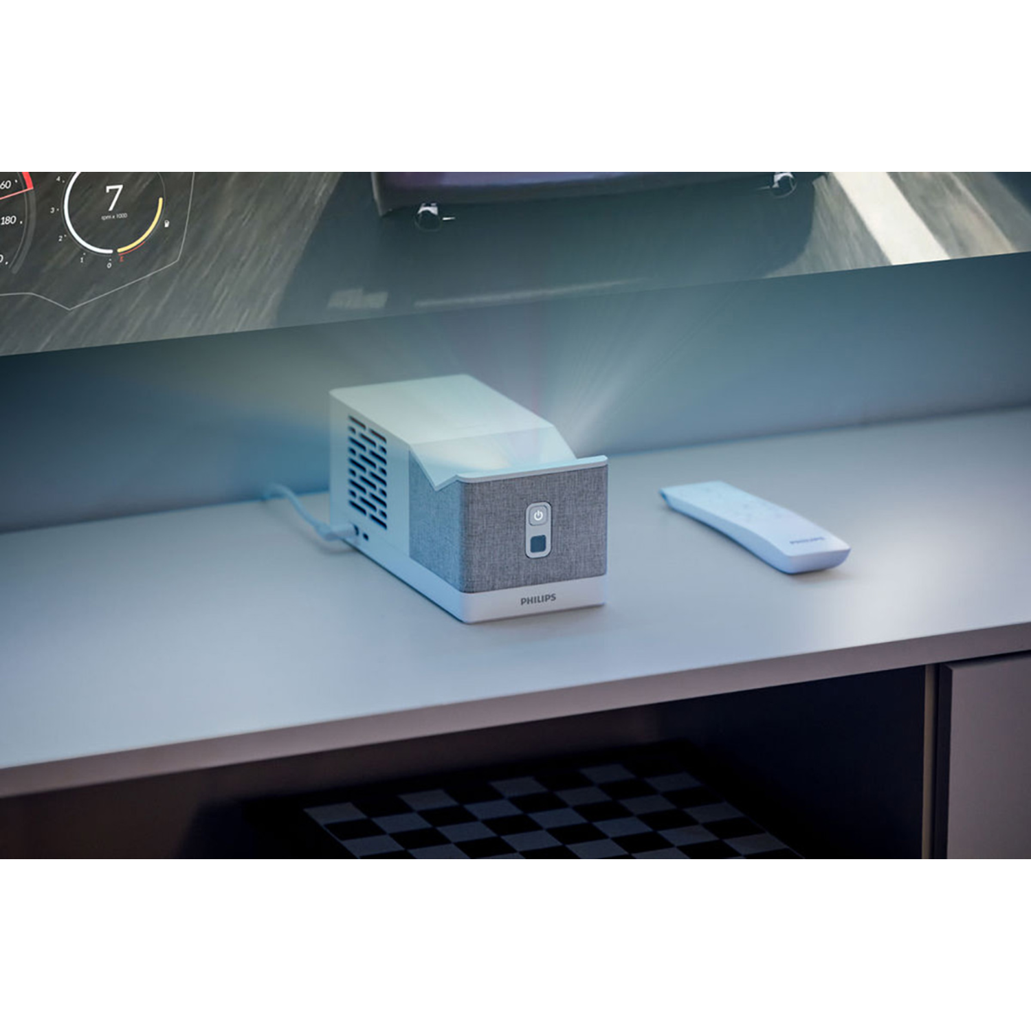 Un projecteur blanc sur une surface blanche avec une télécommande. Un écran avec un indicateur de vitesse en arrière-plan.