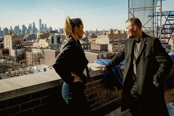 Mann und Frau stehen auf einem Dach mit Stadtblick.