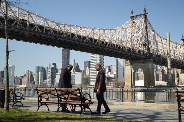 Zwei Männer unter einer Brücke mit Skyline im Hintergrund.