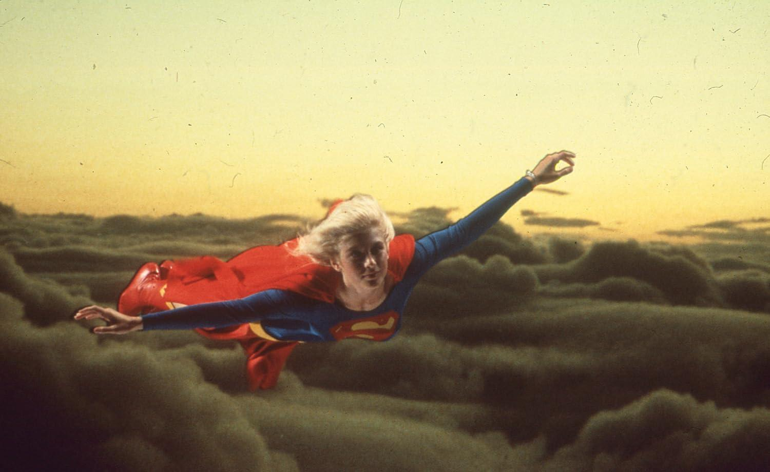 Eine Frau in Superhelden-Kleidung fliegt über Wolken im Sonnenuntergang.