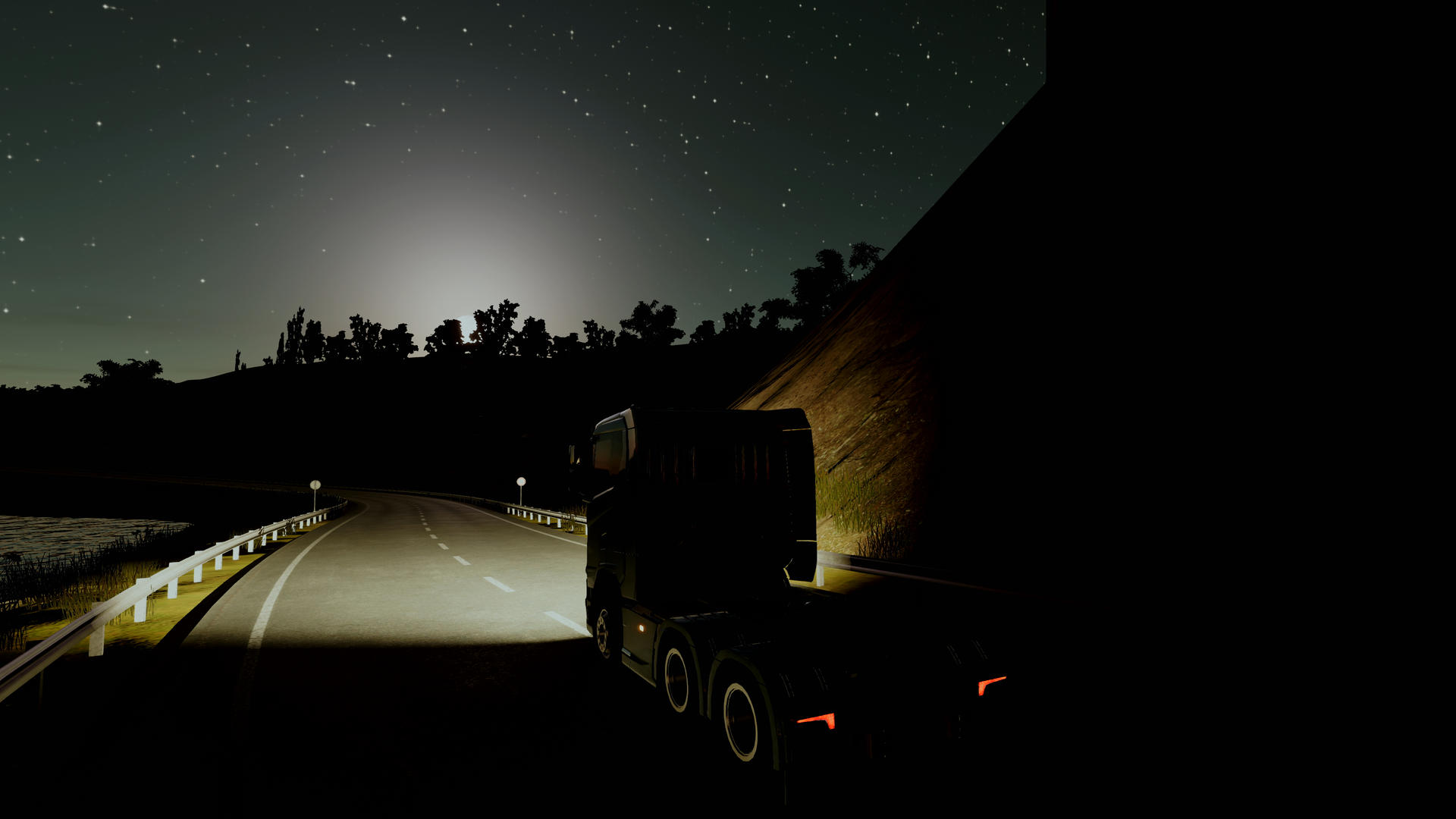 LKW fährt nachts auf dunkler Straße, Scheinwerfer an, mit Sternenhimmel.