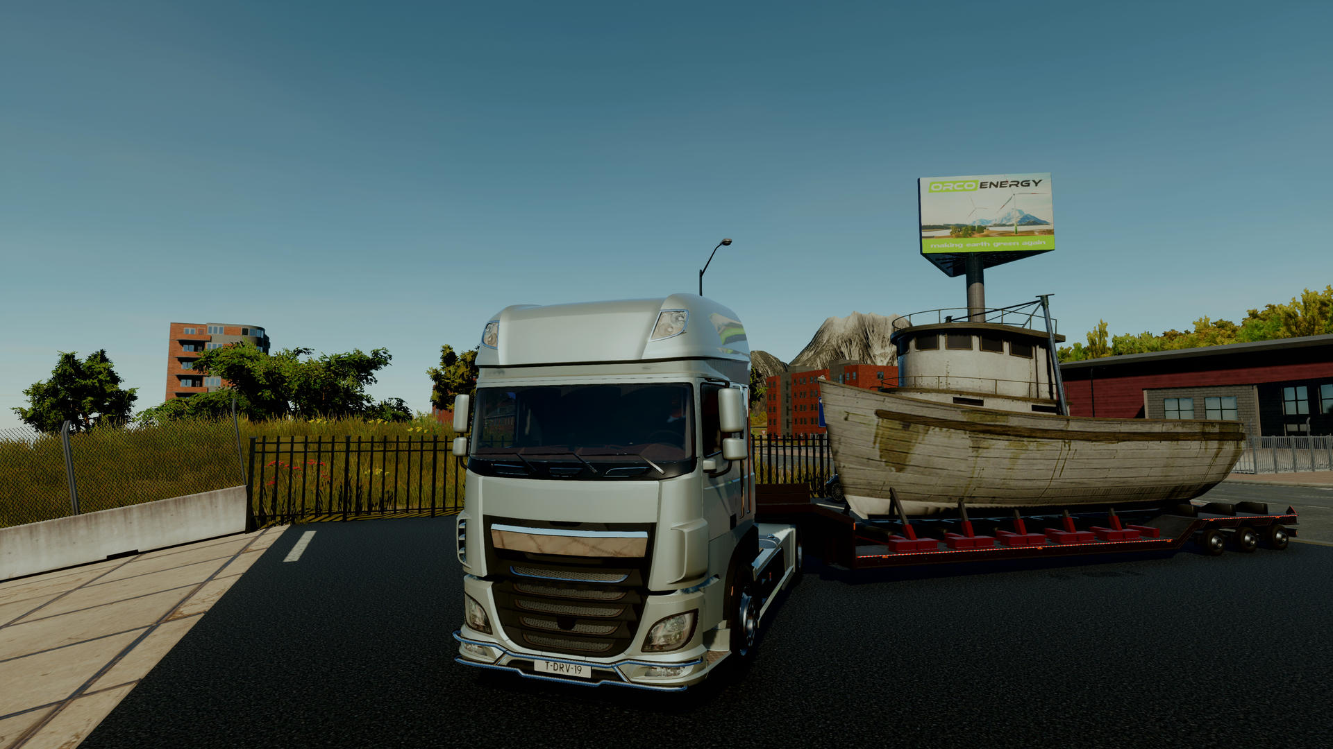 Ein LKW zieht ein Boot auf einem Anhänger an einem sonnigen Tag. Werbetafel im Hintergrund.