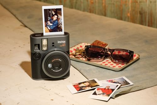 Una cámara Instax con foto impresa, gafas de sol y otras fotos en una superficie.