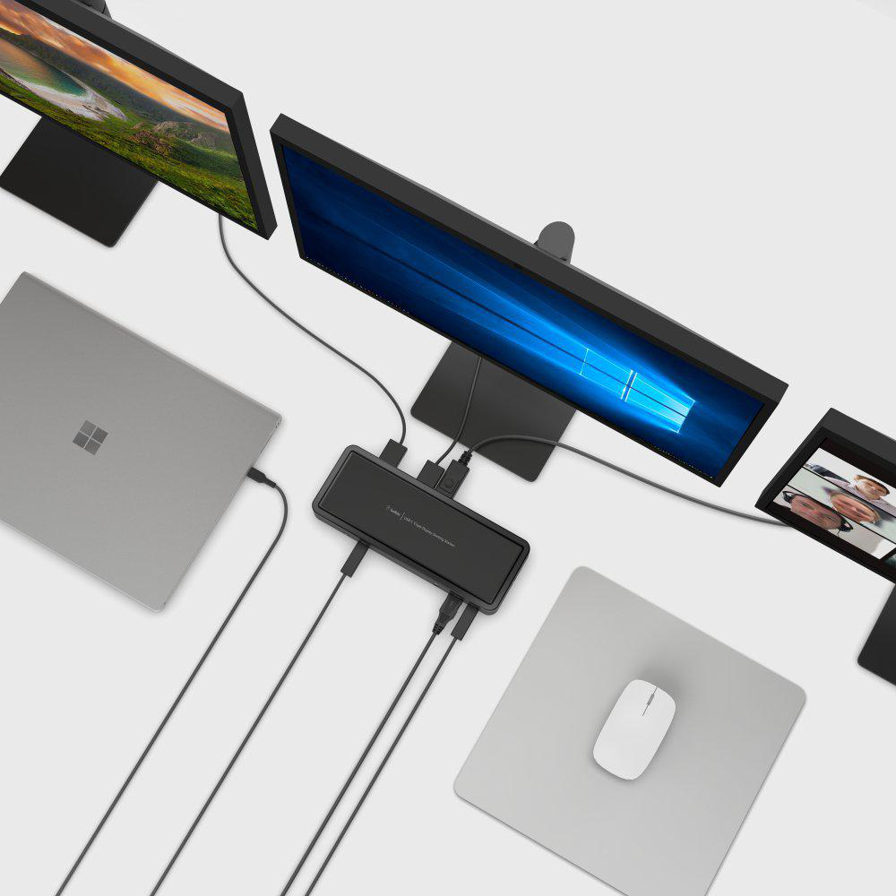 Ein Setup mit mehreren Computermonitoren, einem Laptop und einer Maus auf einer hellen Oberfläche, verbunden durch Kabel.
