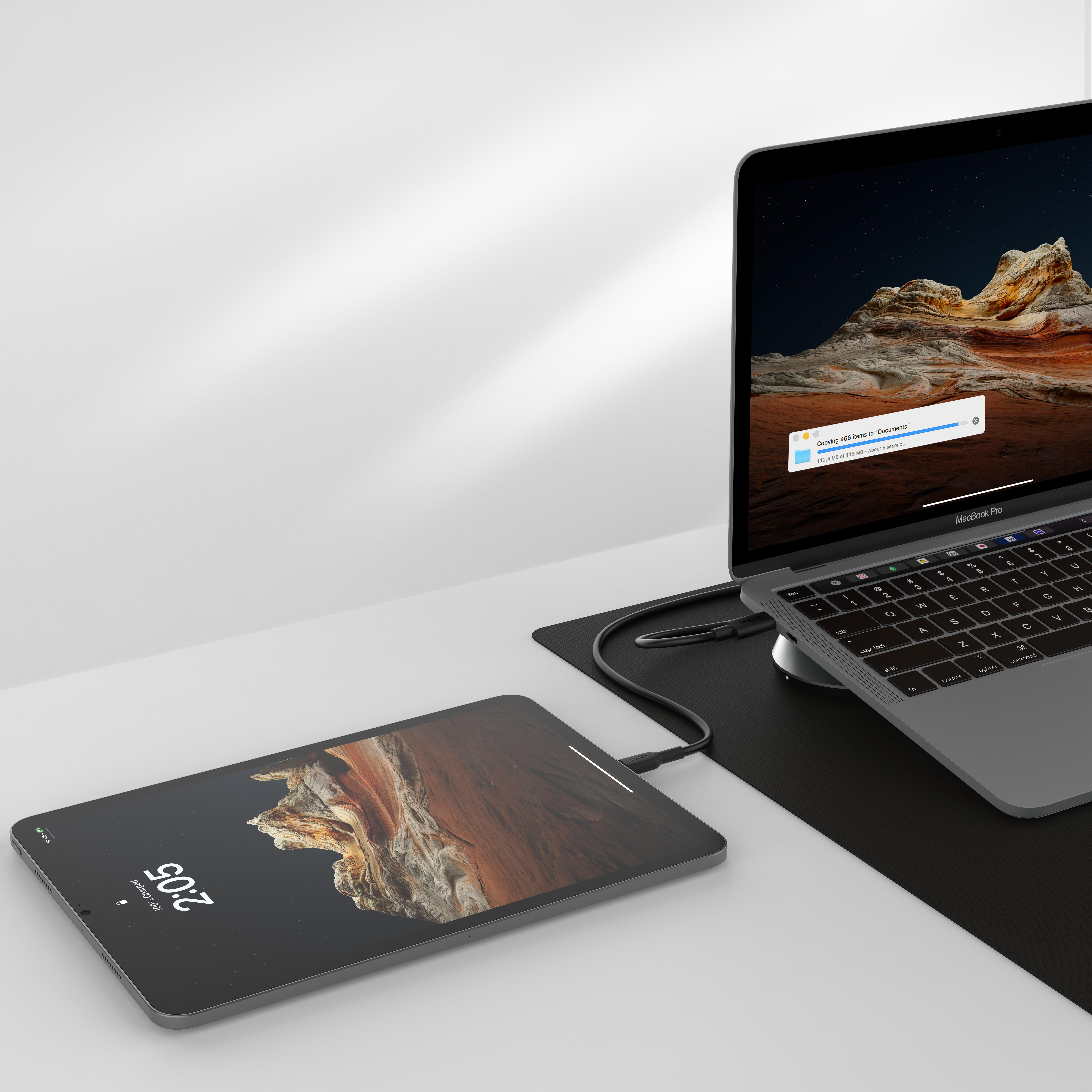 Ein Laptop und ein Tablet sind verbunden. Das Tablet hat eine Uhr und liegt auf einer schwarzen Matte.