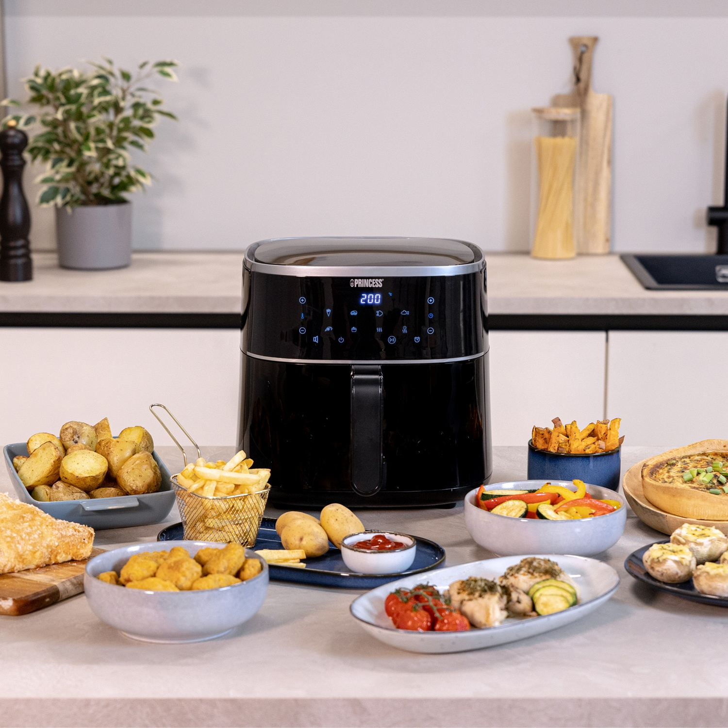 Friggitrice ad aria nera con cibo nei piatti, circondata da ingredienti.