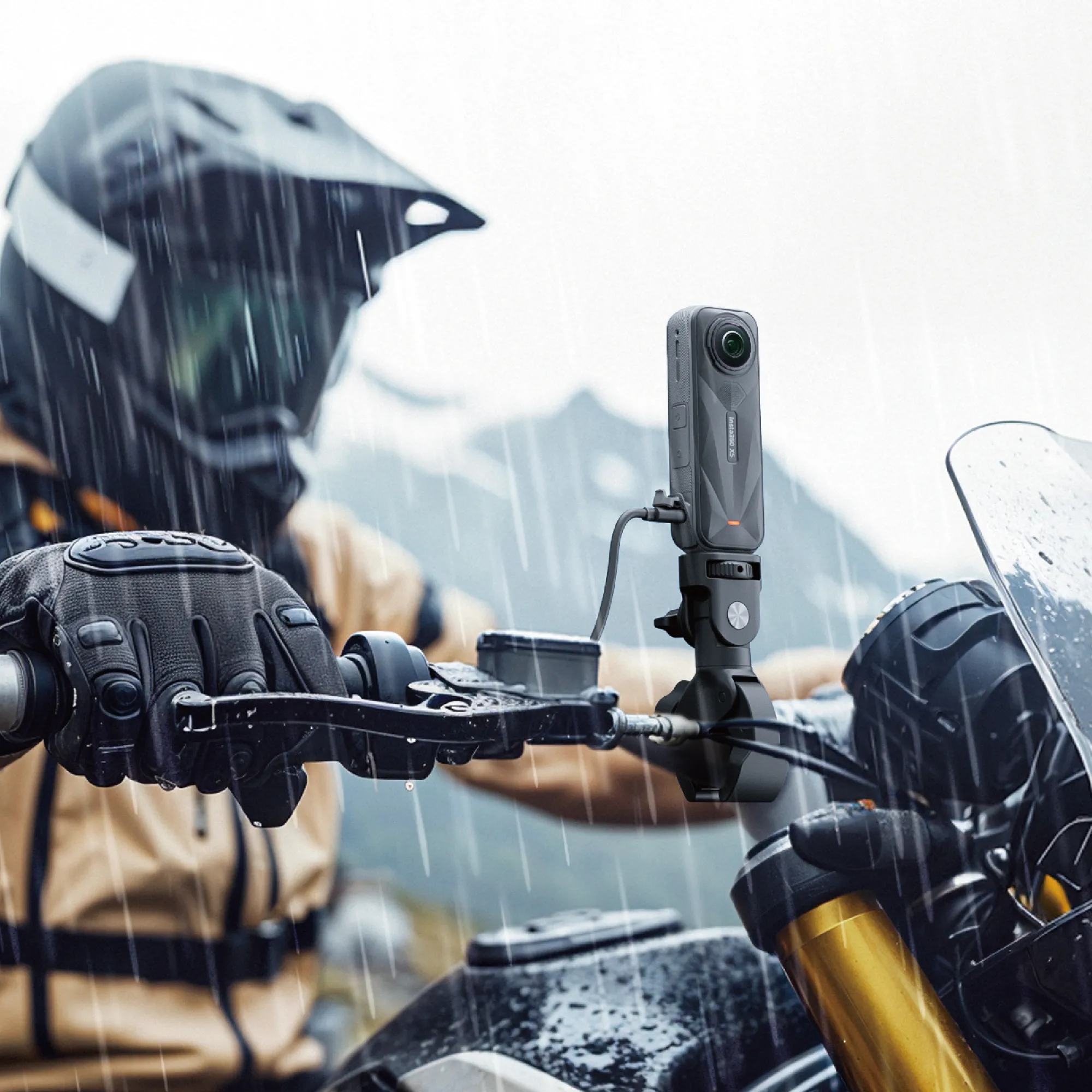 Eine Kamera, die an einem Motorradlenker befestigt ist, mit Regen und Bergen im Hintergrund.
