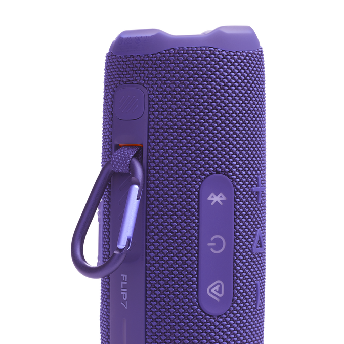 Altavoz morado JBL Flip 7 con mosquetón. Botones laterales. Textura de malla.