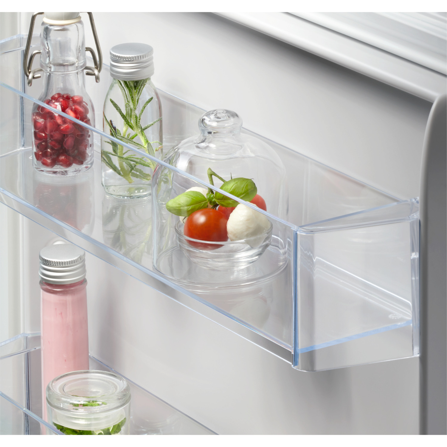 Intérieur de réfrigérateur avec étagères transparentes, bocaux d'ingrédients et aliments frais.