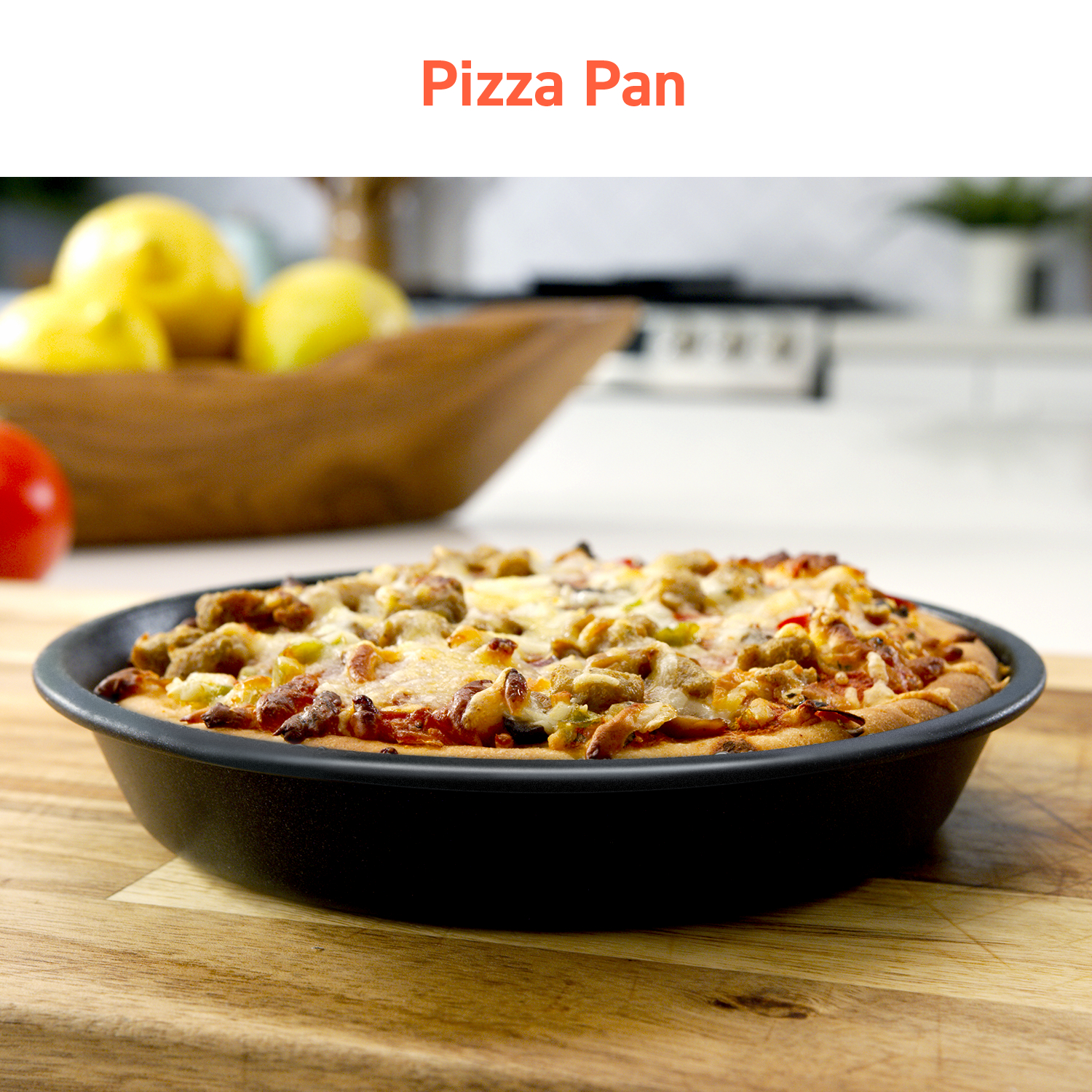 Pizza in a black pan on a wooden surface. The pizza has toppings and is cooked.