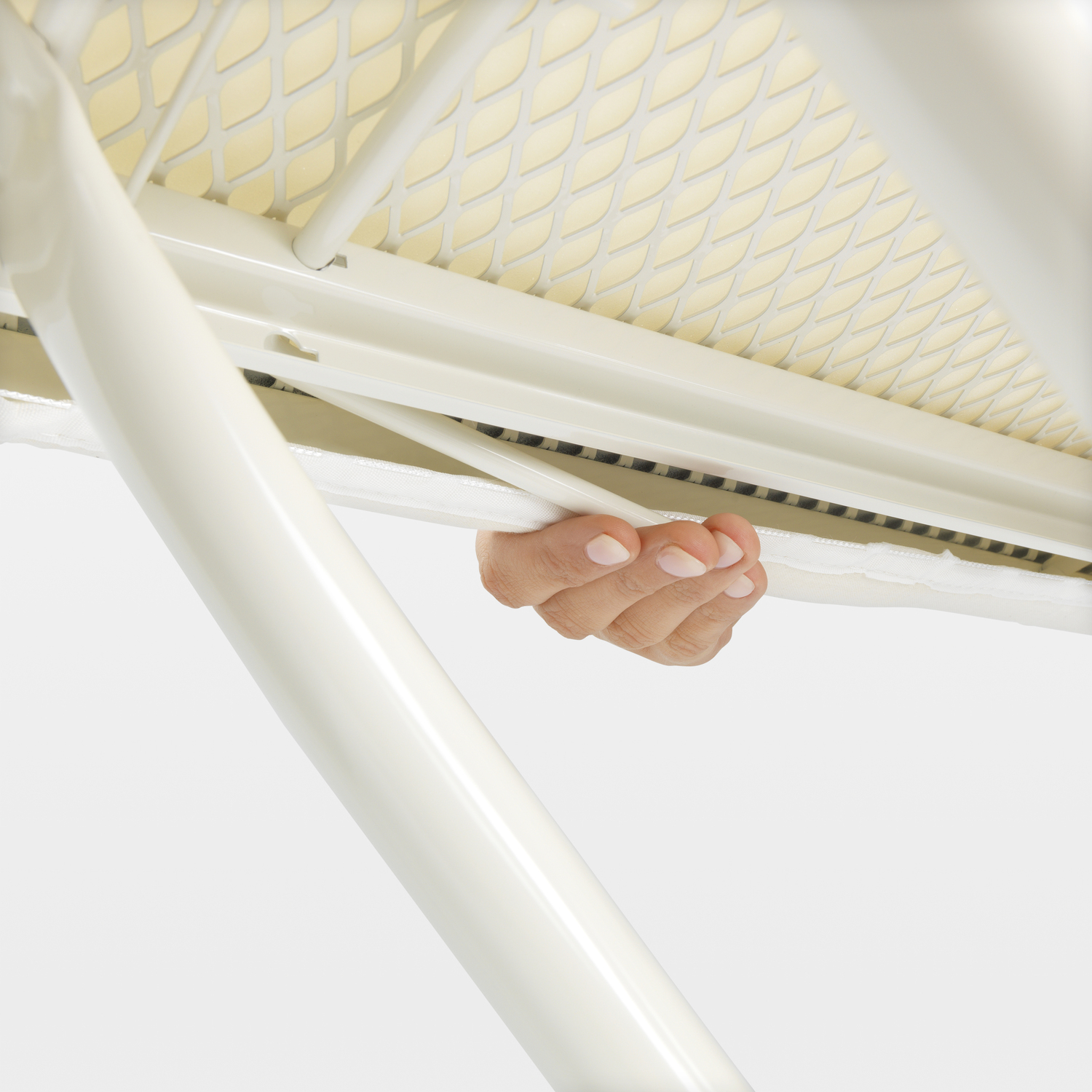 Close-up of a hand holding an ironing board's support. White and cream colors.