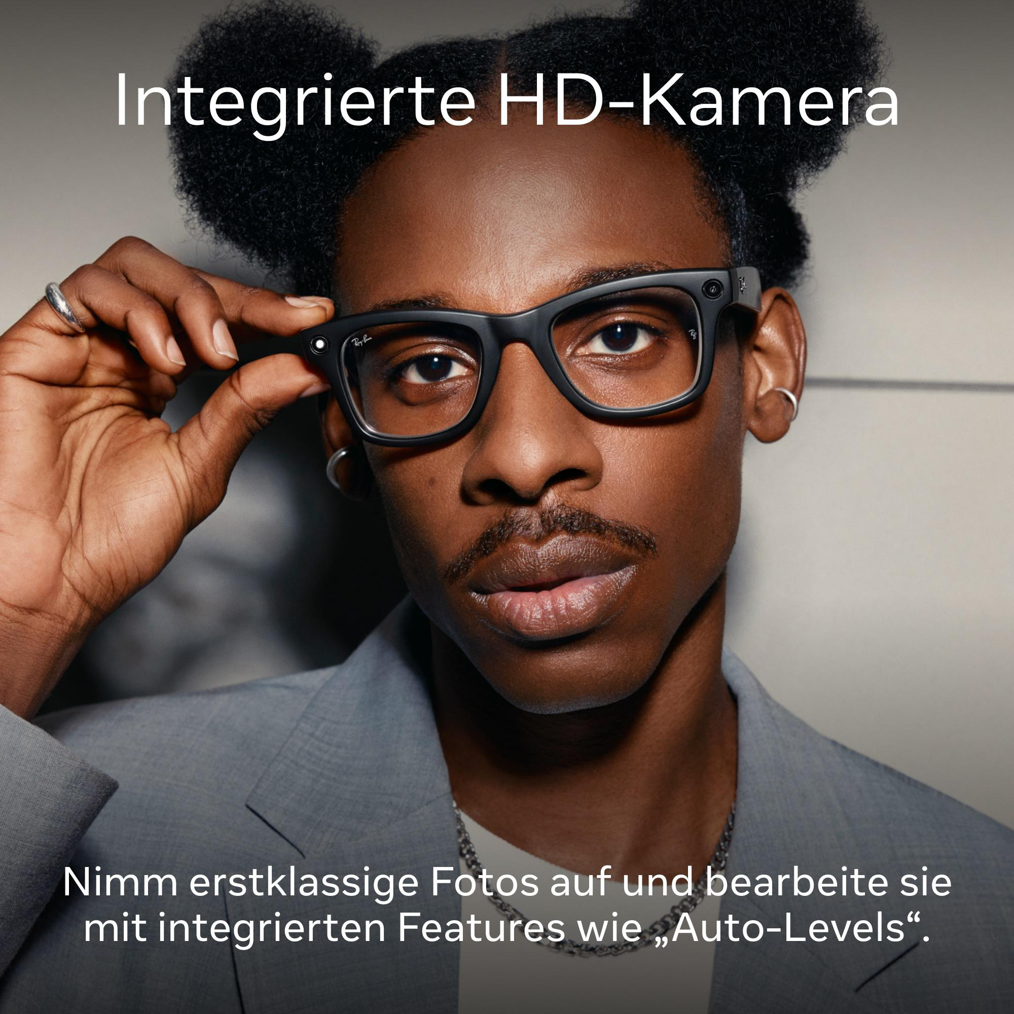 Mann mit Brille, hält sie mit einer Hand hoch und schaut in die Kamera.