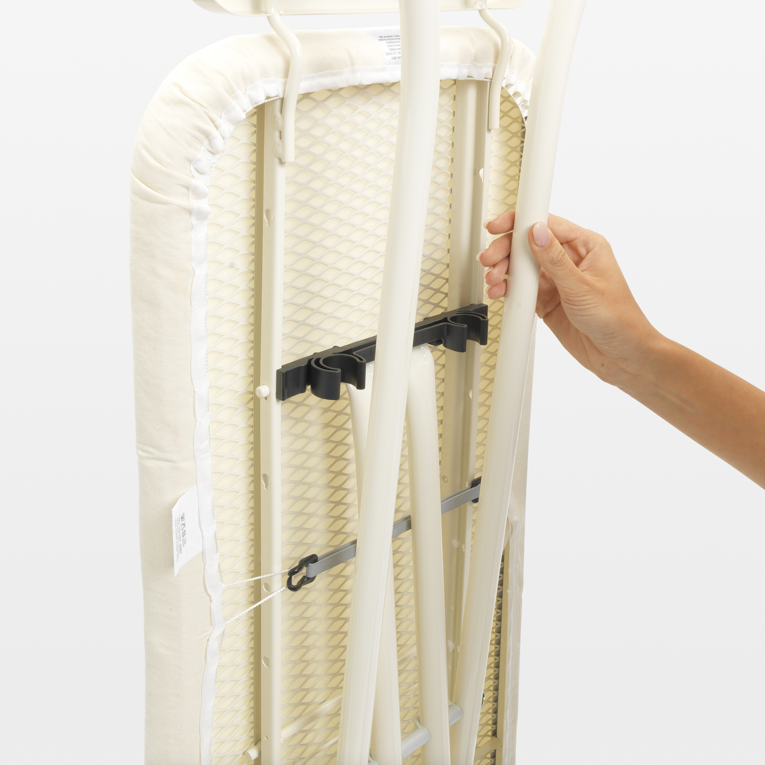 An ironing board with a cover, being folded with a hand.