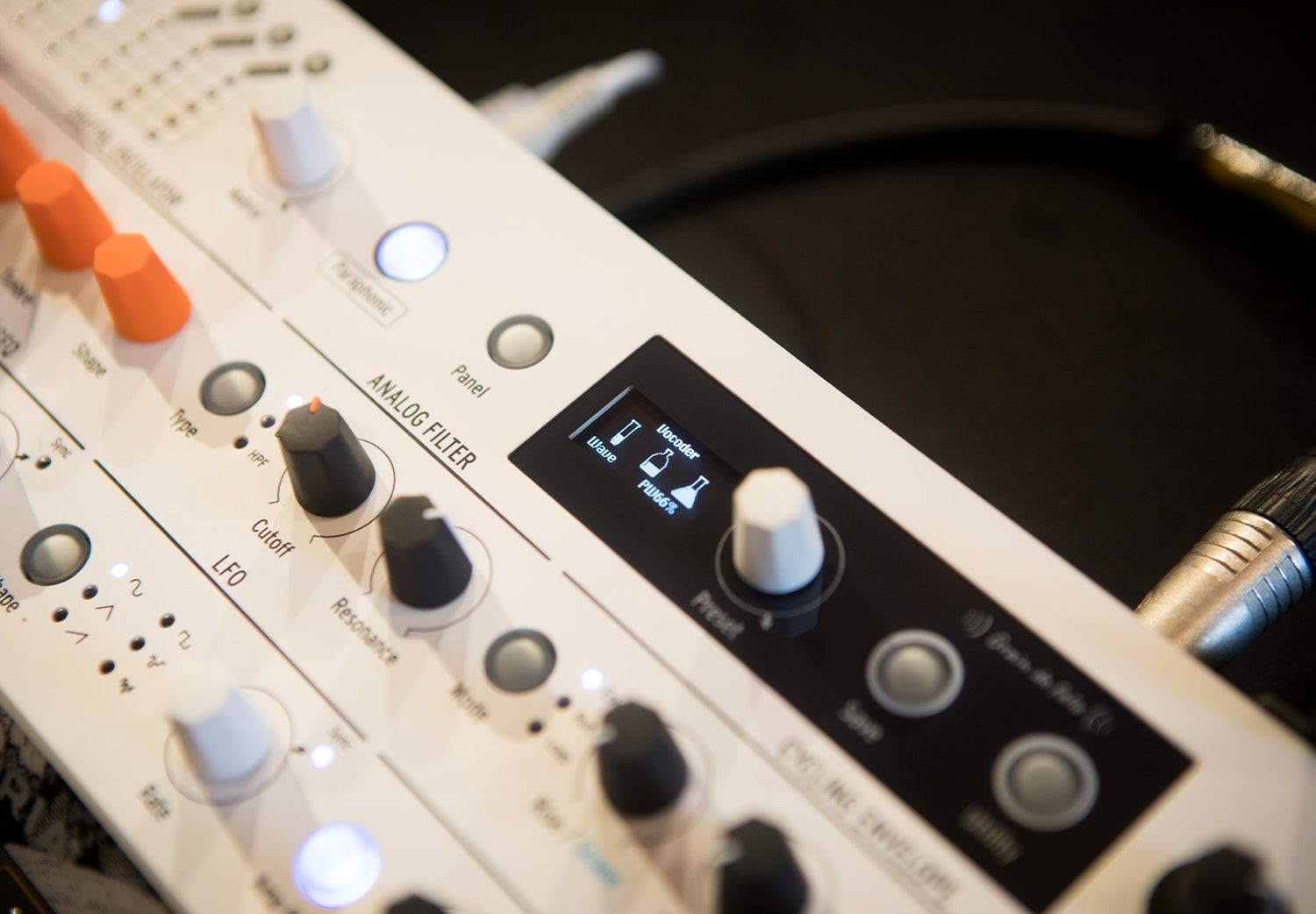 Gros plan sur une table de mixage audio blanche avec des boutons, des boutons et un écran affichant une onde.