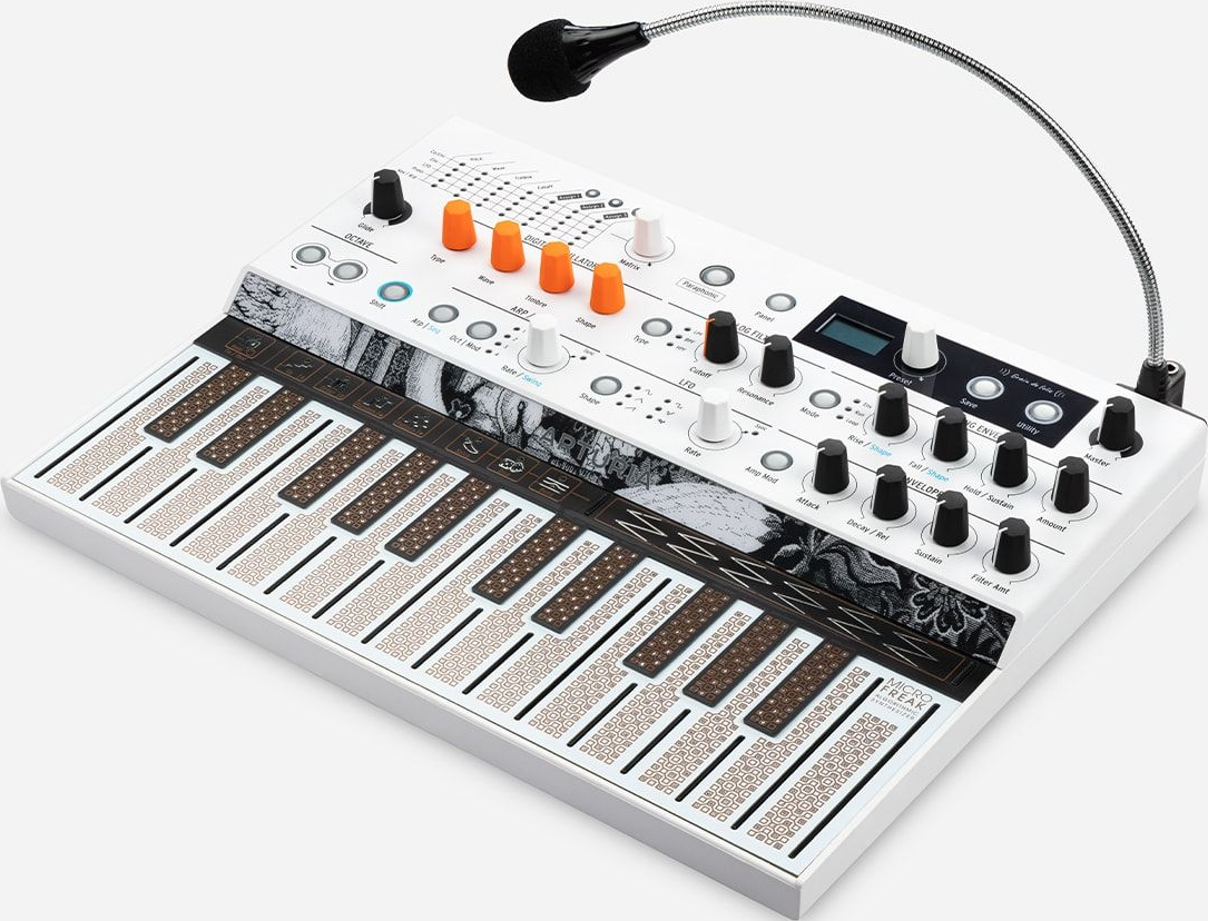 Un synthétiseur blanc avec un microphone, un clavier et divers boutons et curseurs. Accents noirs et oranges.