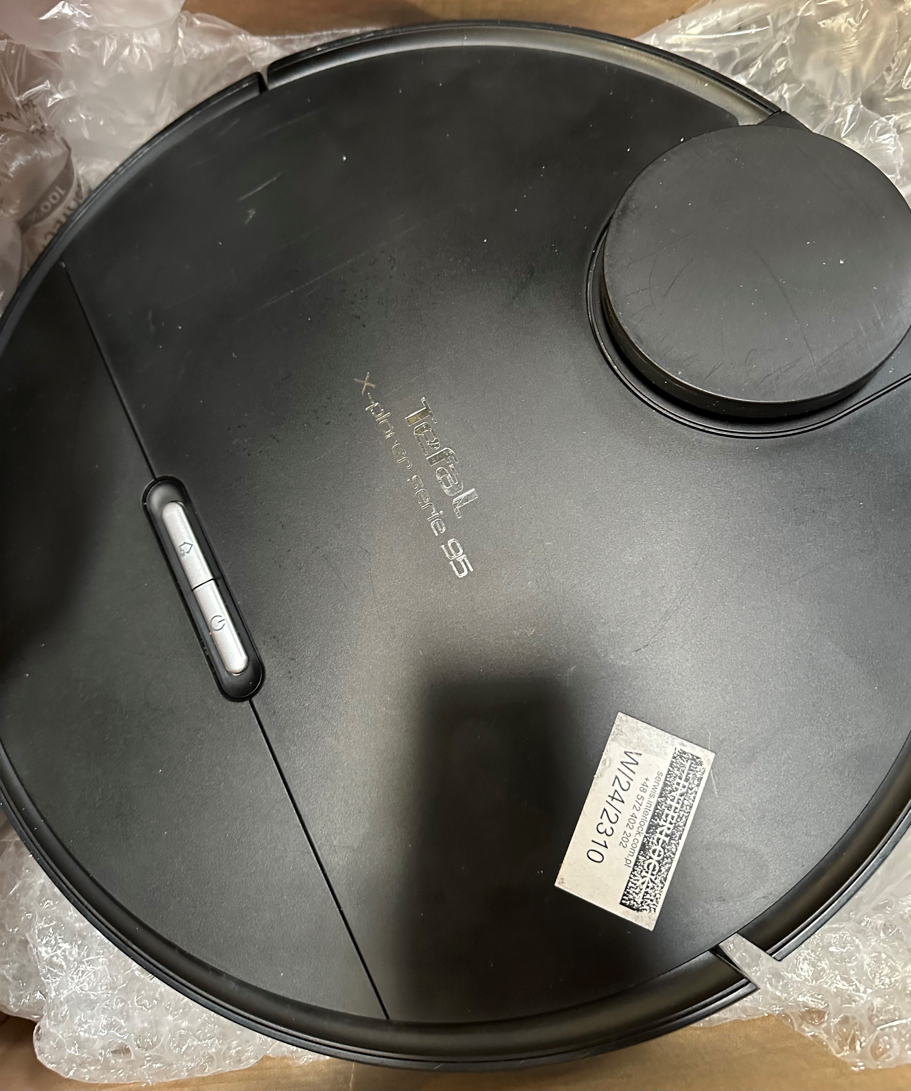 Czarny odkurzacz automatyczny, widok z góry, z logo i naklejką.