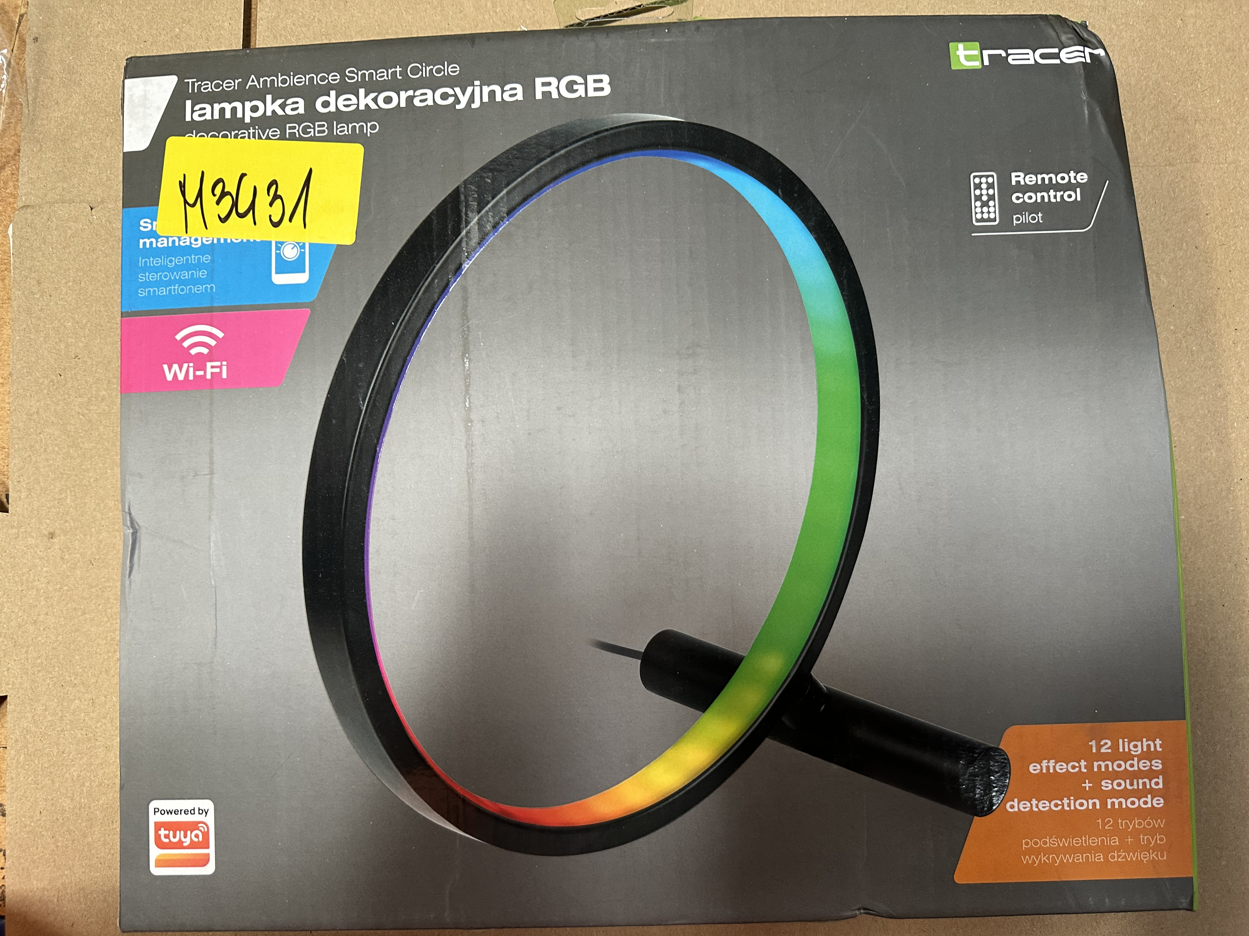 Czarna i kolorowa okrągła lampa LED. Tekst na pudełku i pilot.