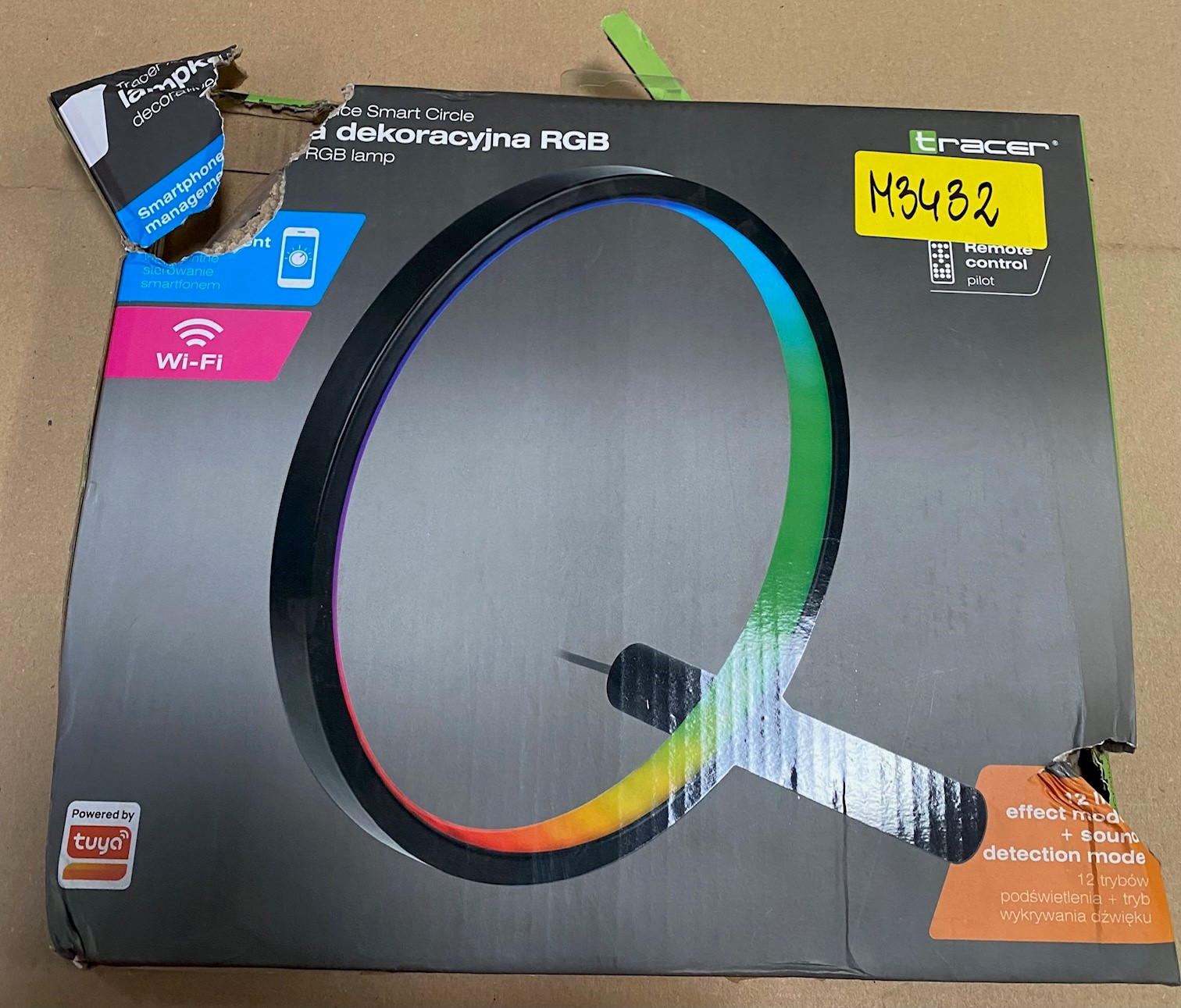 Pudełko z okrągłą lampą RGB w środku. Pudełko ma częściowo rozerwany róg.