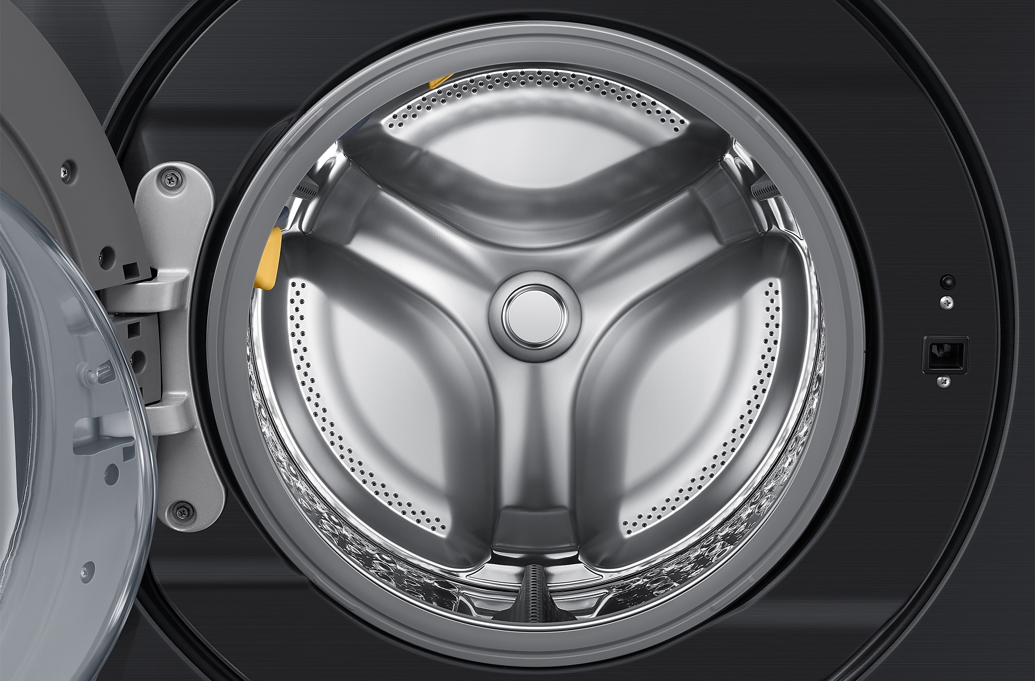Zbliżenie bębna pralki. Stal nierdzewna z otworami i trójramiennym wzorem.