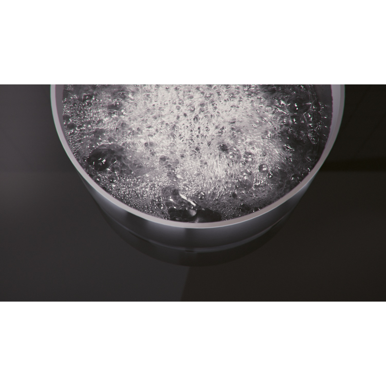 Primo piano di acqua frizzante in un contenitore bianco. L'immagine è dall'alto, sfondo scuro.