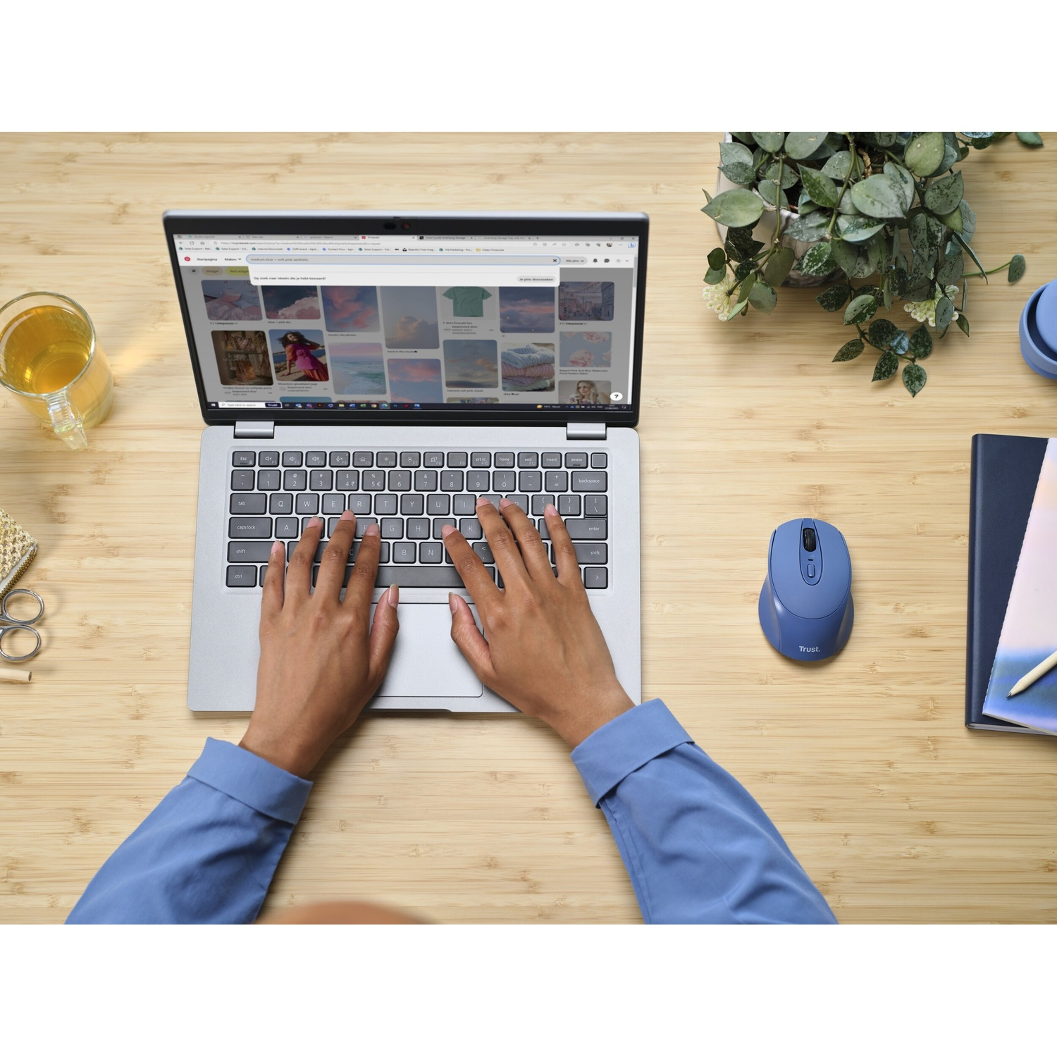 Una persona usa un laptop con un mouse wireless su una scrivania di legno.