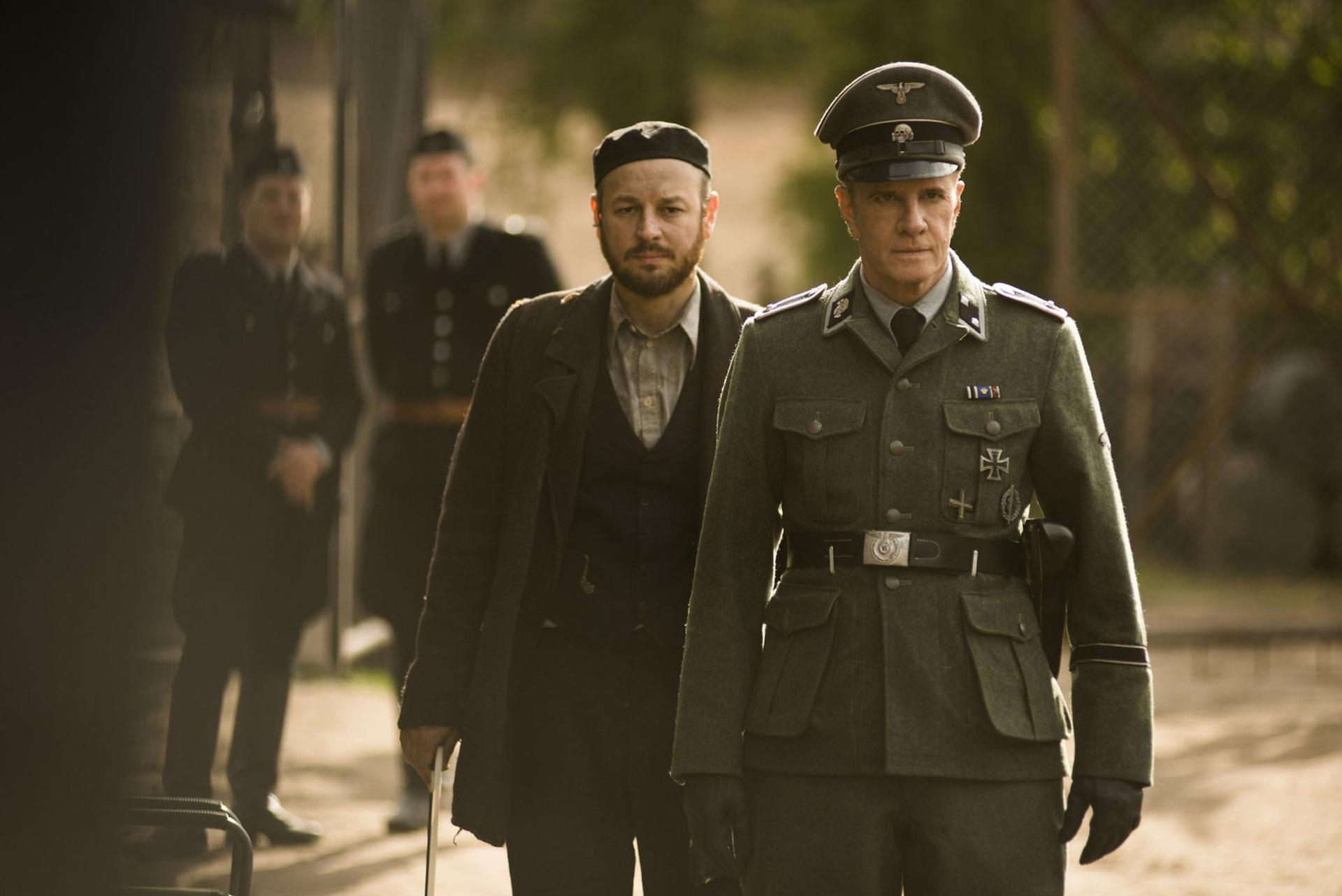 Szene aus einem Film. Zwei Männer in historischer Kleidung, einer in Uniform, draußen.