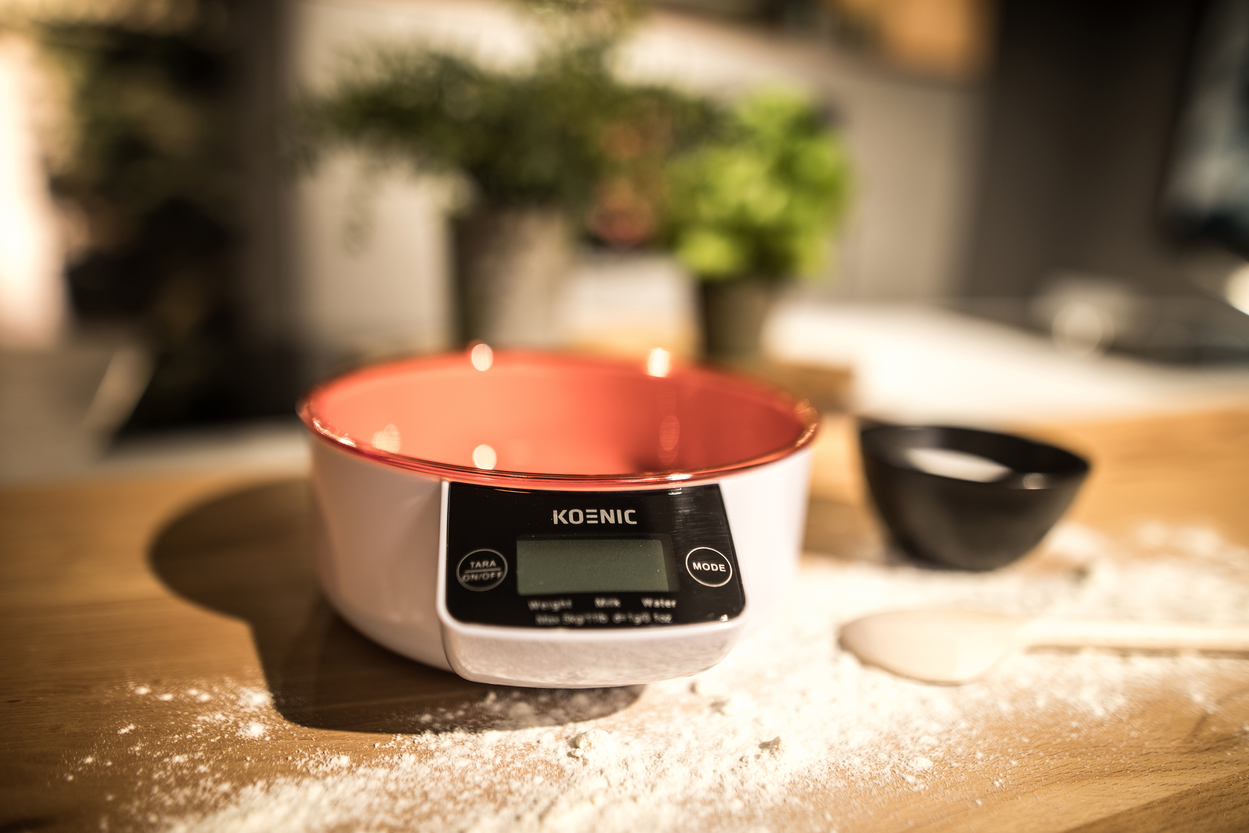 Eine digitale Küchenwaage mit einer roten Schüssel und Mehl.